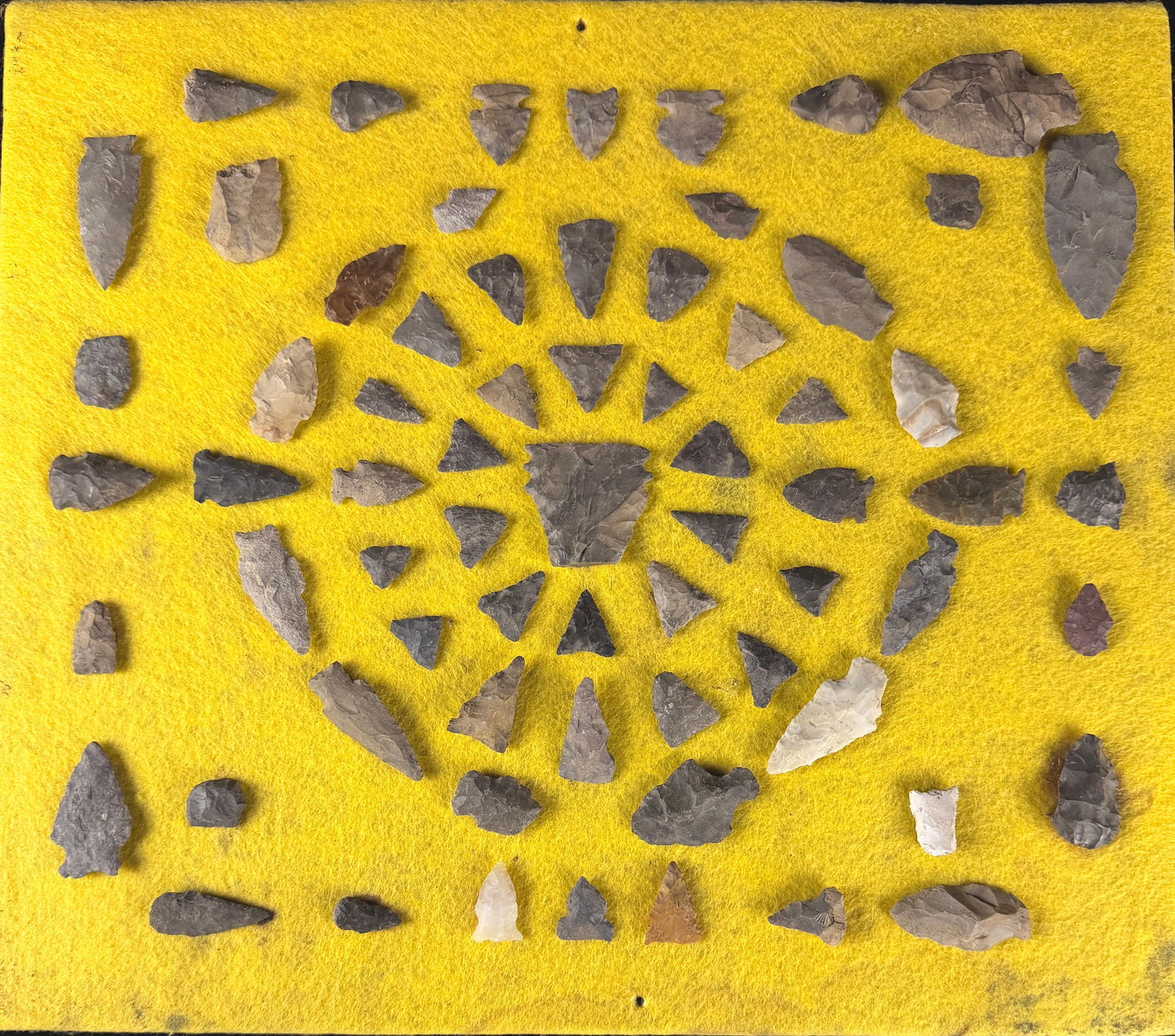A Collection of North American Prehistoric Stone Projectile Points and Lithic Tools: A collection of prehistoric lithic artifacts, likely of North American Indian origin. The items are crafted from knapped stone in various shades of grey, tan, brown, and white, including materials suc