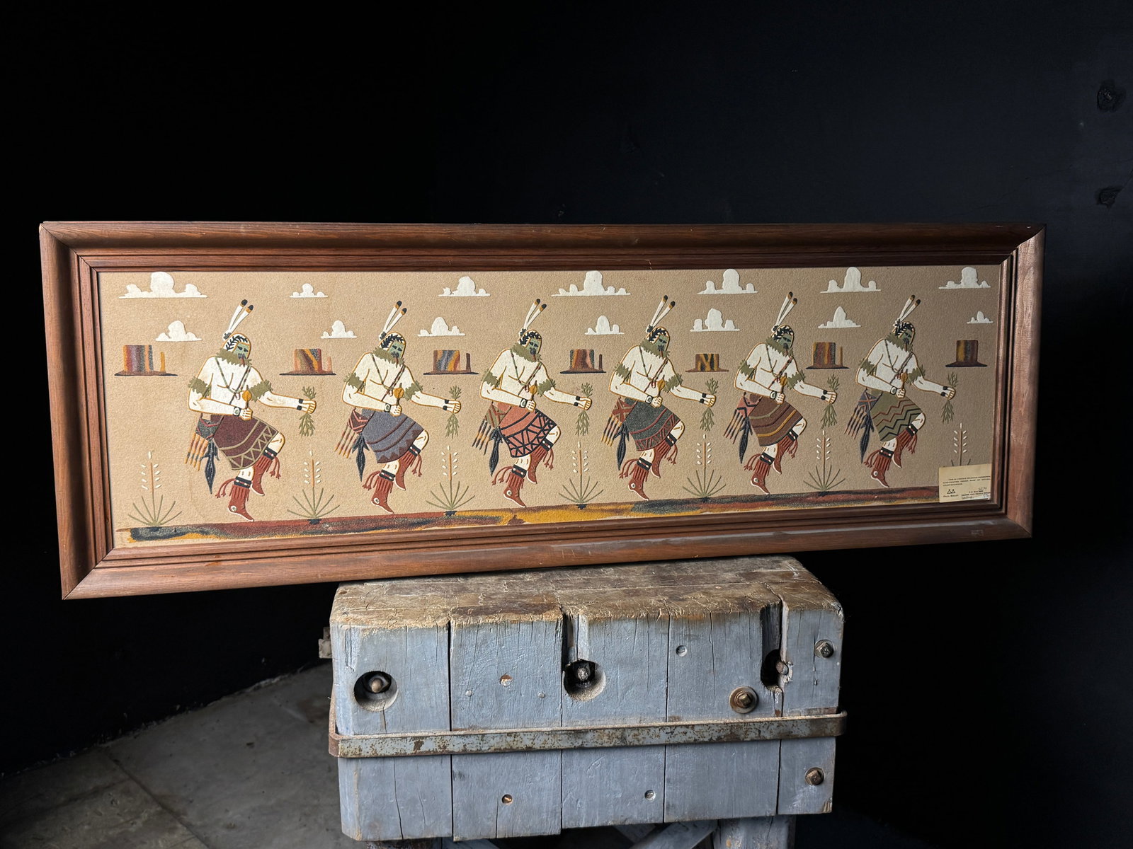 Navajo Yeibechai Sand Painting by Bennie Yazzie and Paul Begay: This lot features a large, horizontally oriented Navajo sand painting depicting the Yeibechai, or Night Chant, ceremonial dance. The work is composed of natural colored sandstone on board and illustra