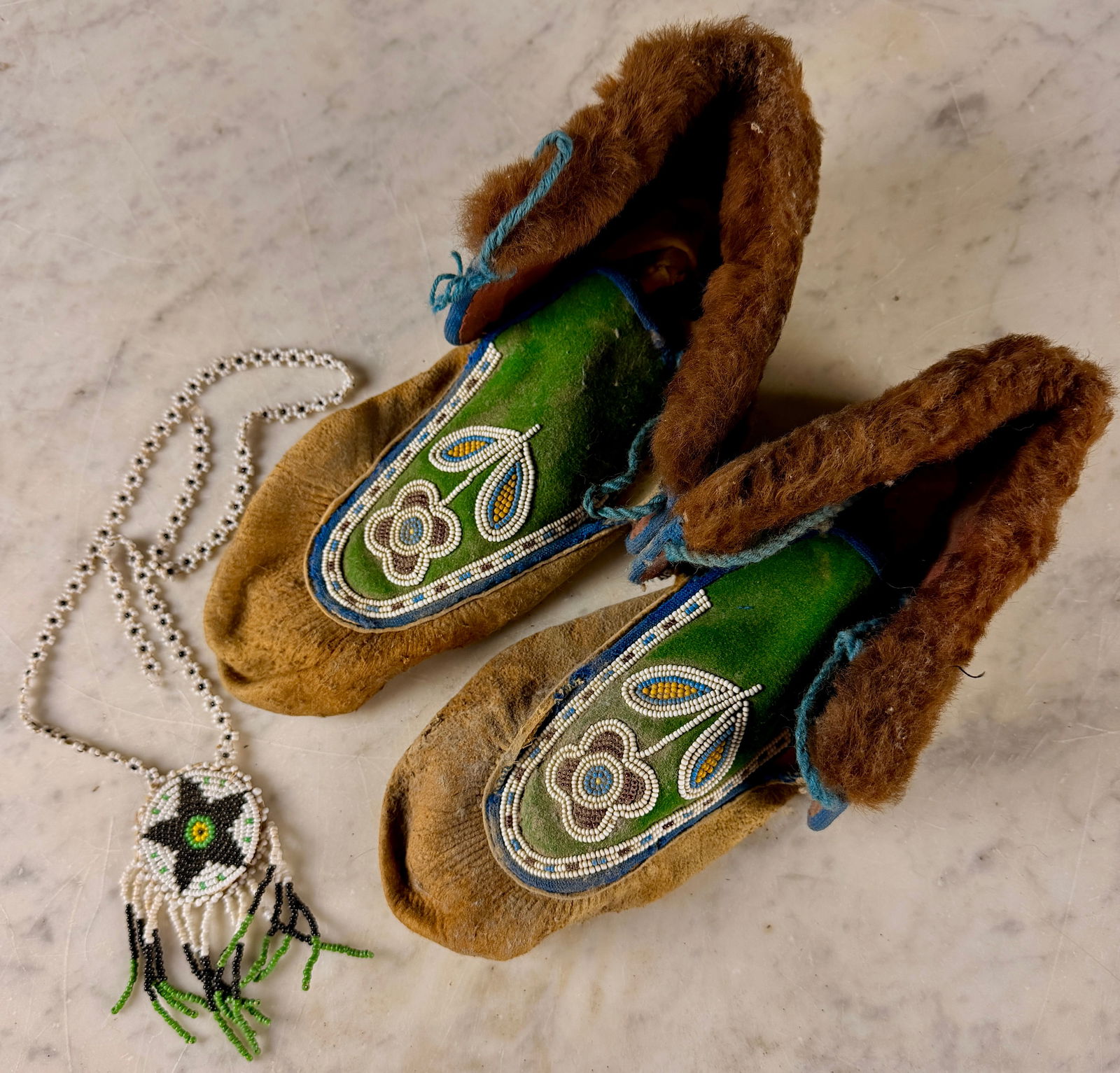 A Trio of Native American Woodlands Style Beaded Items: This group consists of a pair of handcrafted moccasins and a coordinating medallion necklace, attributed to the Woodlands region, likely Iroquois or Seneca. The moccasins are constructed from tan leat