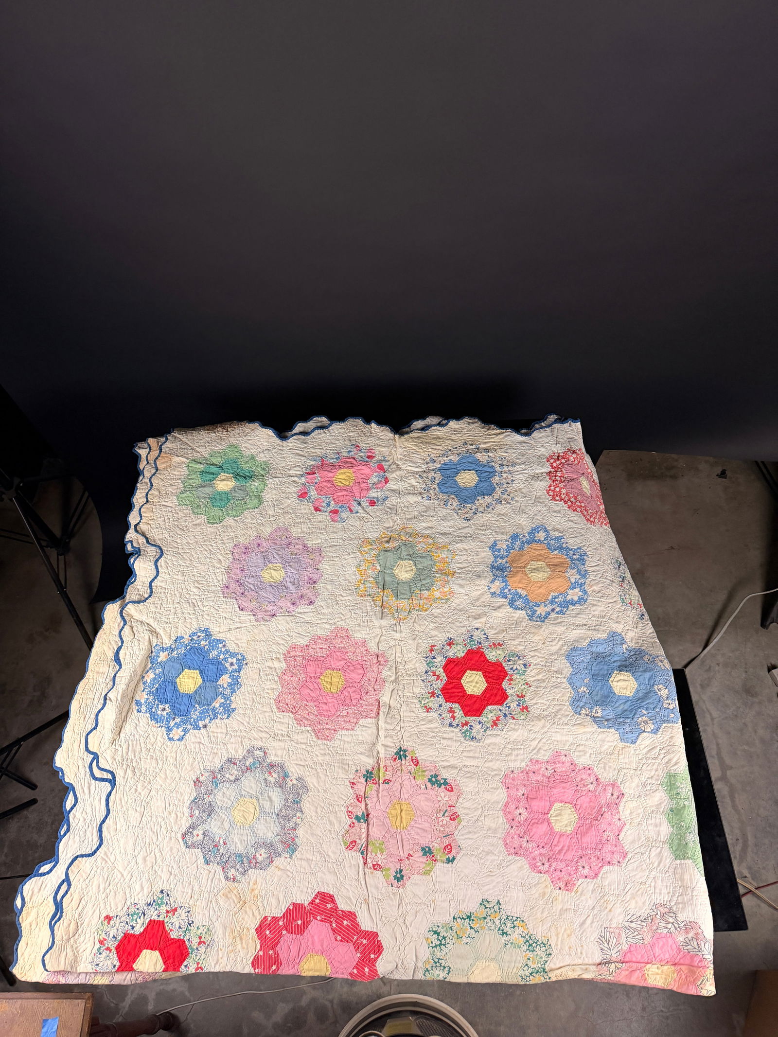 Vintage Grandmother's Flower Garden Quilt: A mid-20th-century cotton quilt featuring the traditional Grandmother's Flower Garden pattern. The textile is composed of numerous hand-stitched hexagonal patches in various floral prints and solid
