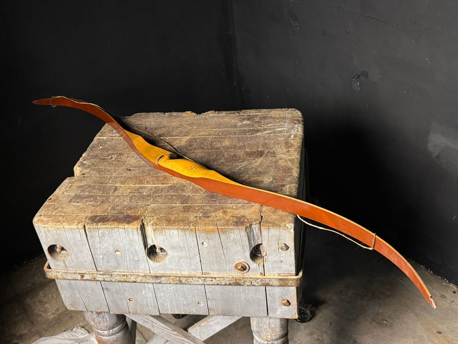 A Vintage Nighthawk Laminated Wood Recurve Bow: A vintage recurve bow featuring a light-toned wooden riser and reddish-brown laminated limbs. The model name Nighthawk is printed in yellow script on the limb. The riser is marked with specifications