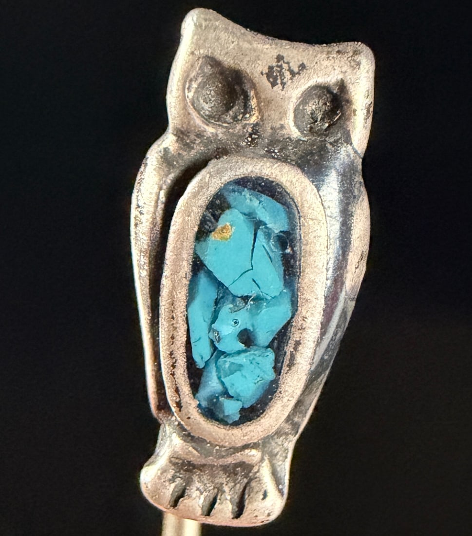 Southwestern Style Silver Tone Owl Stick Pin with Turquoise Chip Inlay: A Southwestern style stick pin featuring a stylized owl motif. The head of the pin is constructed from silver-tone metal and depicts an owl with recessed circular eyes and a central oval-shaped apertu