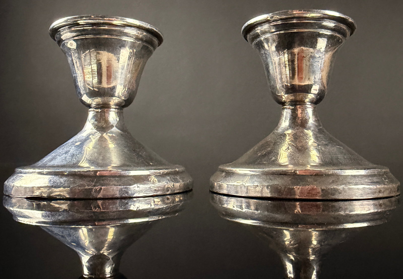 A Pair of American Silver Co. Weighted Sterling Silver Candlesticks: This pair of low candlesticks is manufactured by the American Silver Co. of Bristol, Connecticut. Each piece is constructed from sterling silver over a weighted base for stability. The design features
