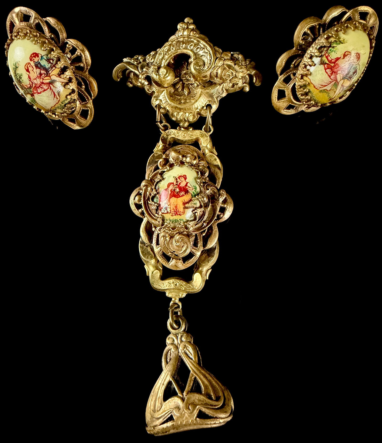 Karu Fifth Avenue Neo-Rococo Style Courting Couple Pendant Brooch and Earring Suite: A costume jewelry suite by Karu Fifth Avenue featuring a multi-tier pendant brooch and a pair of matching clip-on earrings. The pieces are constructed from gold-tone cast metal with ornate openwork sc