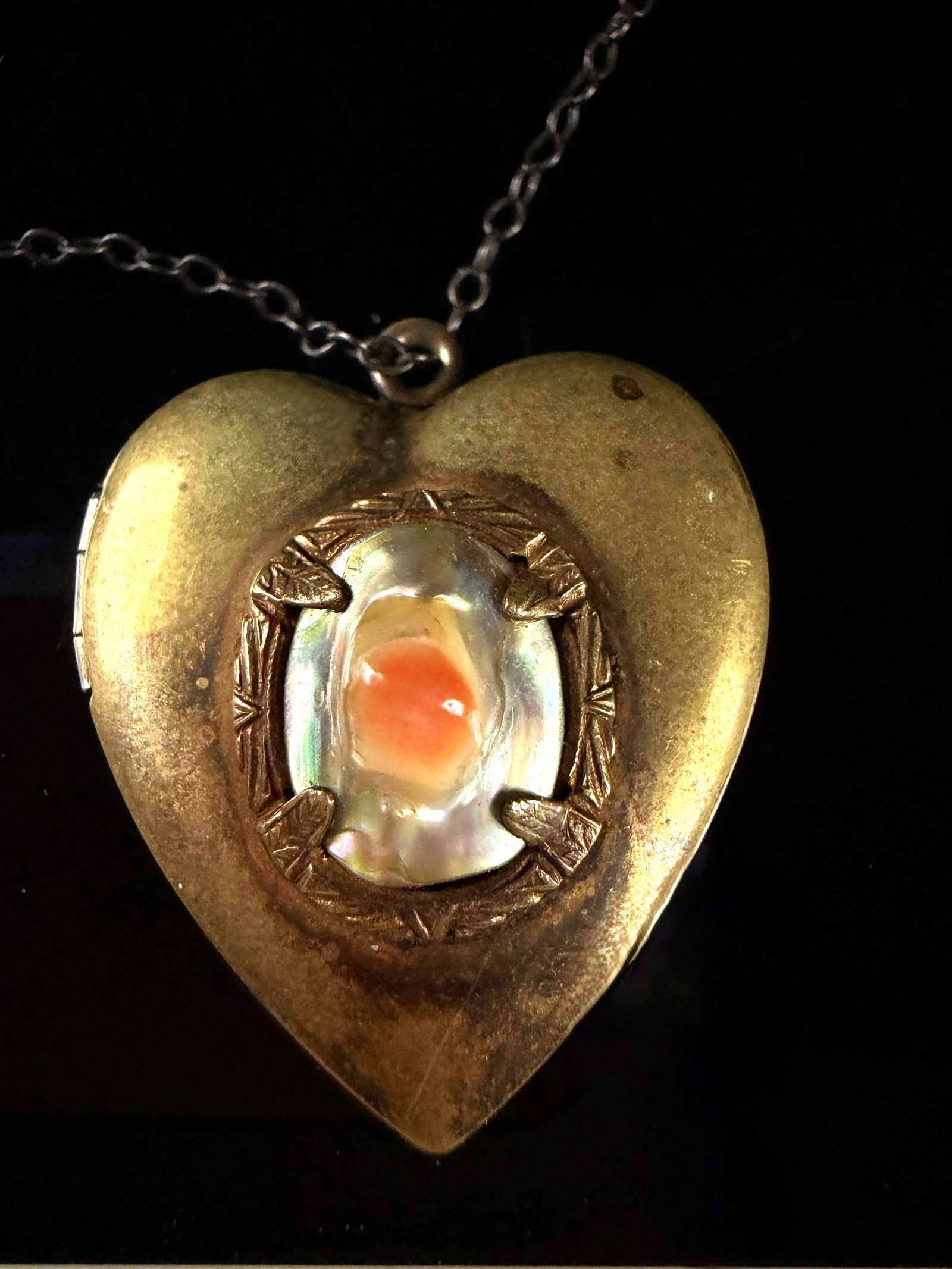 Vintage Gold-Tone Heart Locket Necklace with Blister Pearl Insert: A heart-shaped locket pendant suspended from a fine cable link chain. The locket is constructed from gold-tone metal. The front face features a central oval blister pearl or mother-of-pearl insert wit