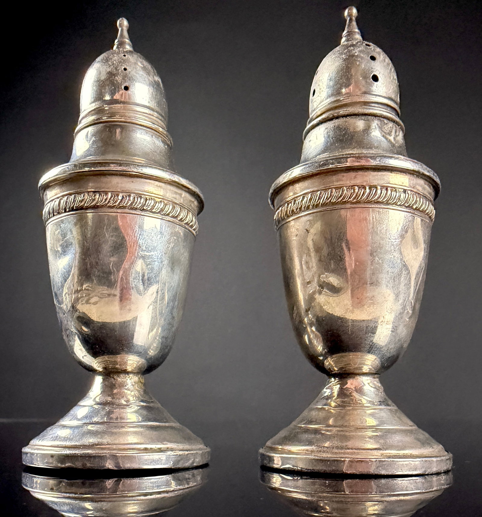 A Pair of Crown Silver Co. Sterling Silver Weighted Salt and Pepper Shakers: This pair of salt and pepper shakers is produced by the Crown Silver Co. Inc. of New York. Each piece is crafted in sterling silver and features a weighted base for stability. The shakers are designed
