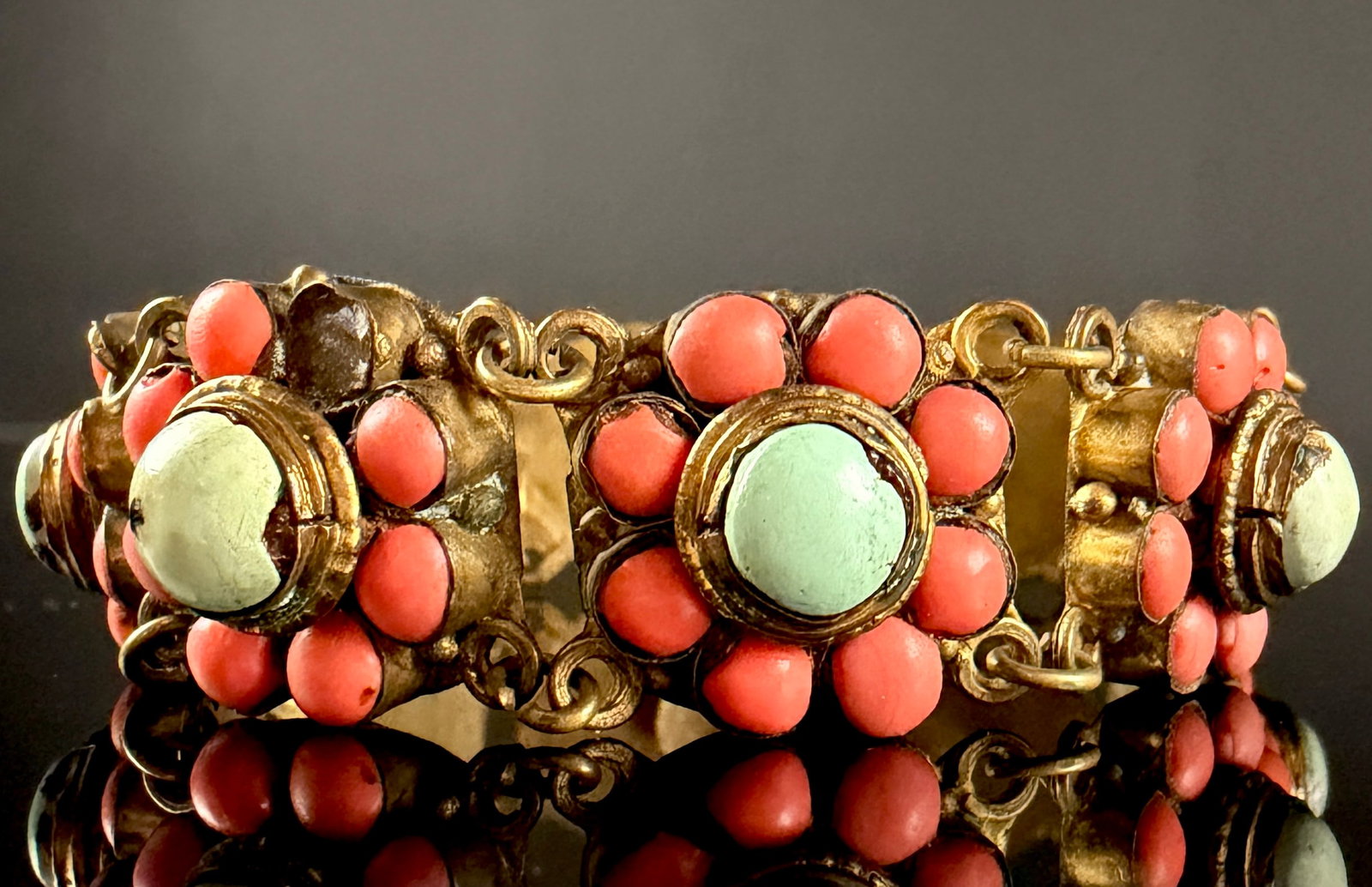 Vintage Gilded Base Metal Floral Panel Bracelet with Turquoise and Coral Colored Stones: This linked panel bracelet features eight square decorative links, each designed with a floral motif. Every panel is set with a central light-green cabochon, likely turquoise, which exhibits a natural