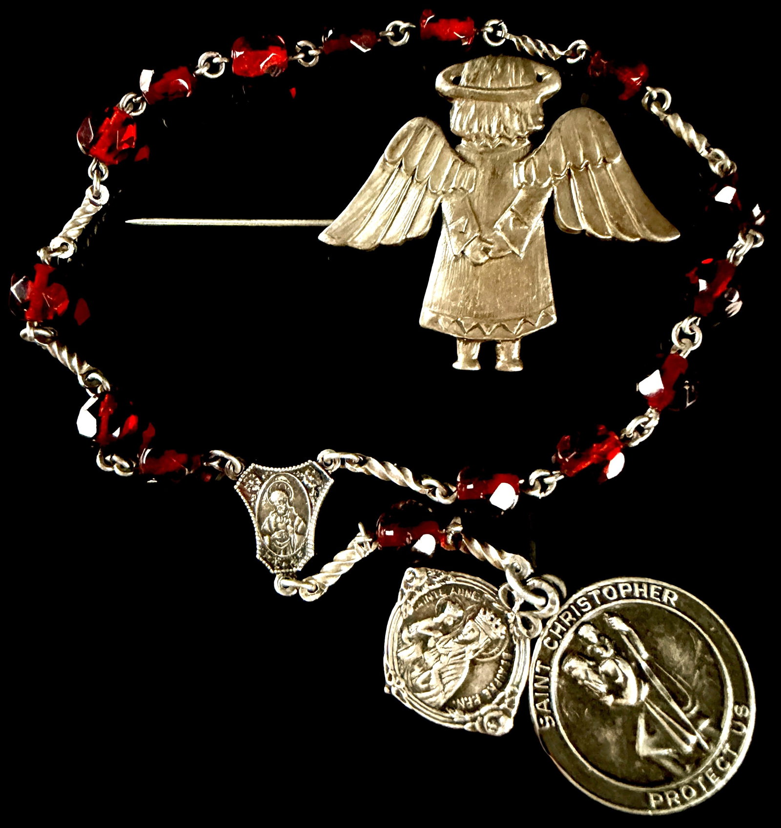 Two Sterling Silver Religious Items Including a Malco Devotional Chain and a JJC Angel Brooch: This lot features two sterling silver devotional items. The first is a single-decade rosary-style devotional chain composed of twelve faceted red glass beads connected by twisted wire links. The chain
