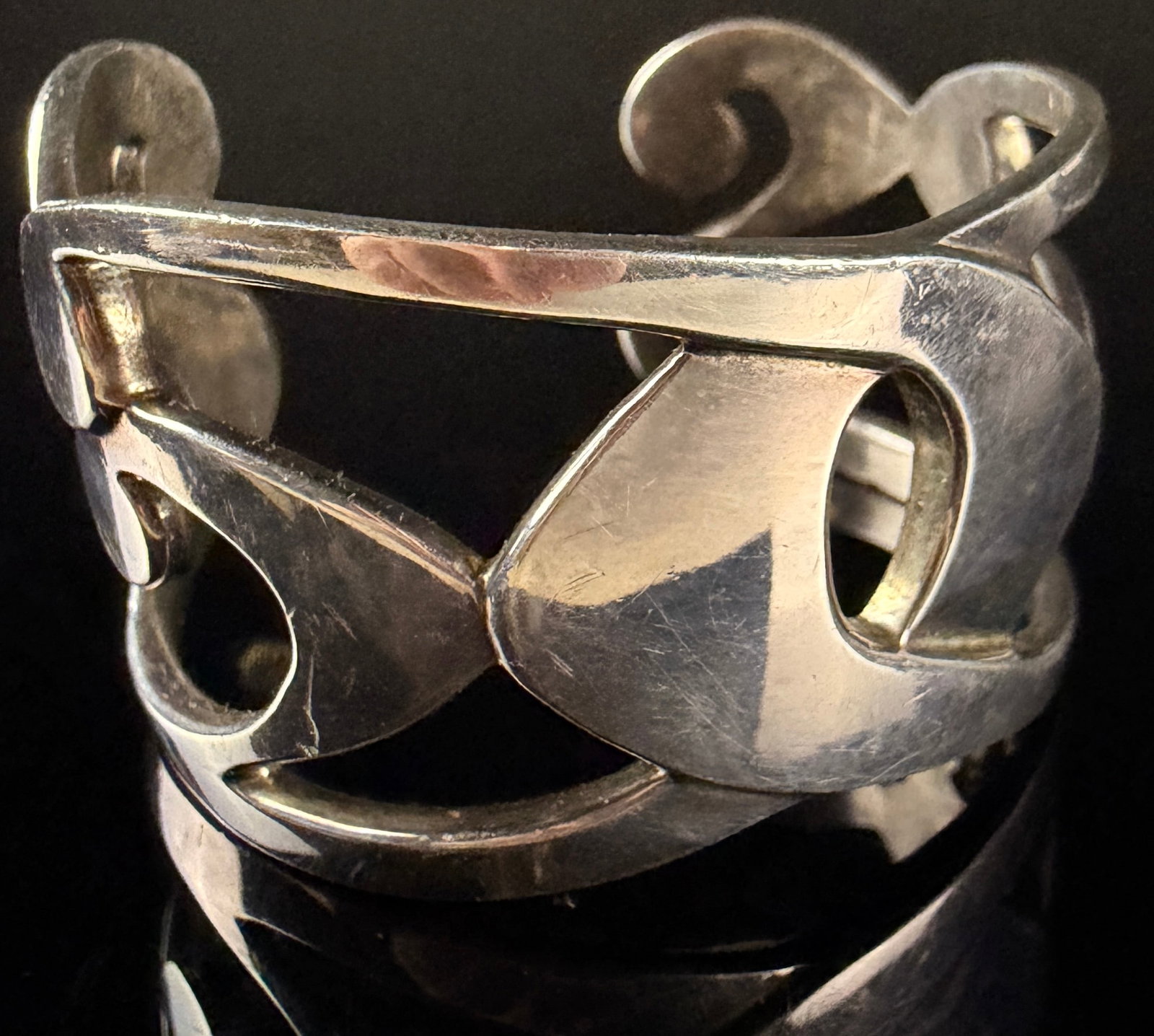 Modernist Sterling Silver Openwork Cuff Bracelet: This modernist cuff bracelet is crafted from sterling silver and features a bold, sweeping curvilinear openwork design with a polished finish. The interior of the cuff is stamped with a rectangular 92