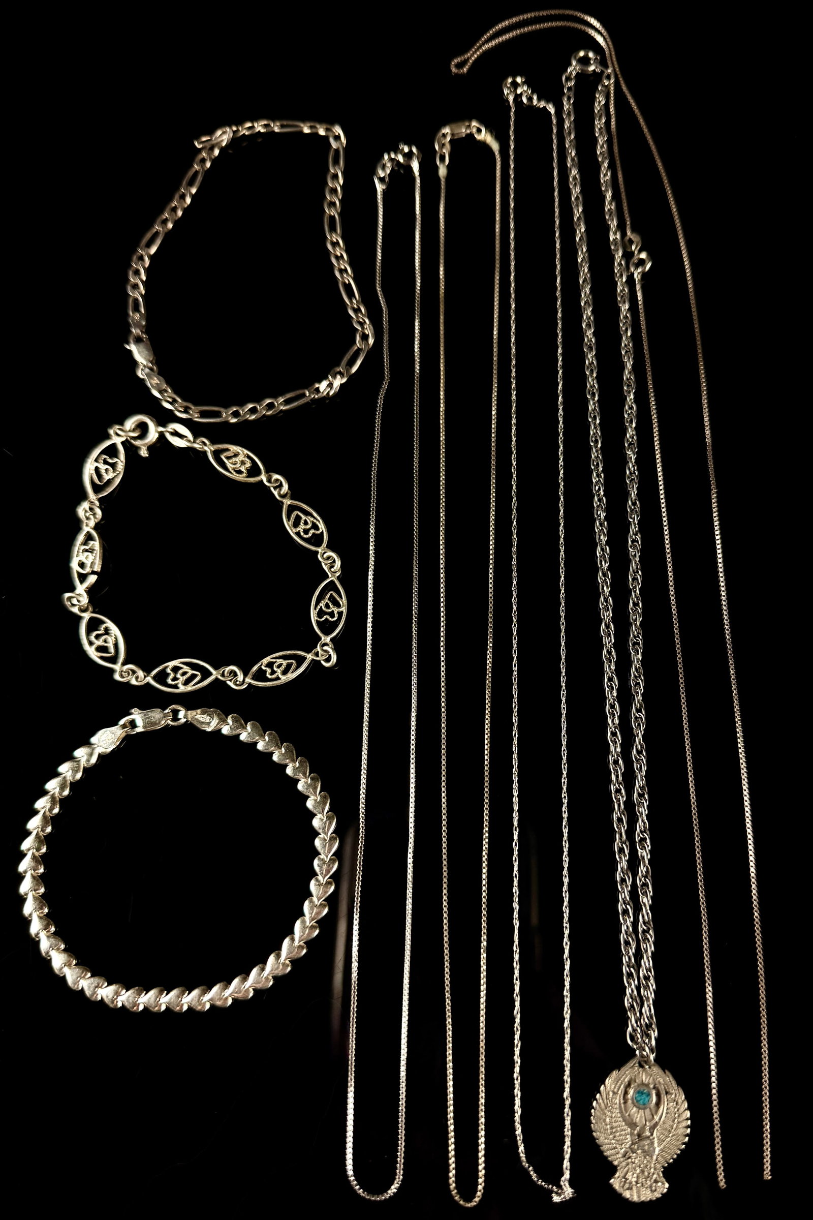 A Collection of Sterling Silver Bracelets and Necklaces: A collection of sterling silver jewelry pieces comprising three bracelets and seven necklaces. The bracelets consist of one figaro link chain with a lobster claw clasp, one decorative open link chain