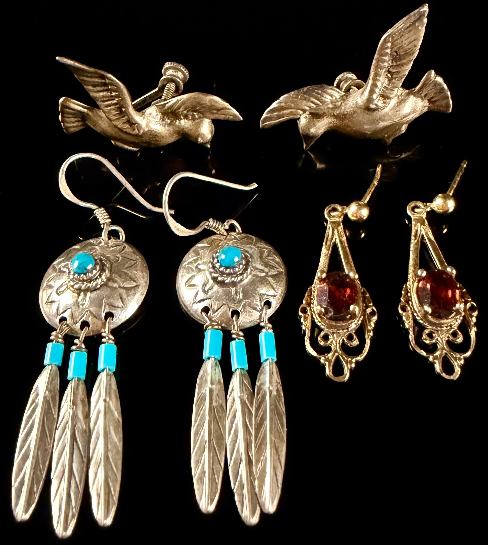 Vintage Sterling Silver Earrings Including Navajo Style Turquoise and Garnet Filigree: This collection consists of three matched pairs of vintage sterling silver earrings in various styles. The first pair is a set of Navajo style dangle earrings. Each earring features a central round tu