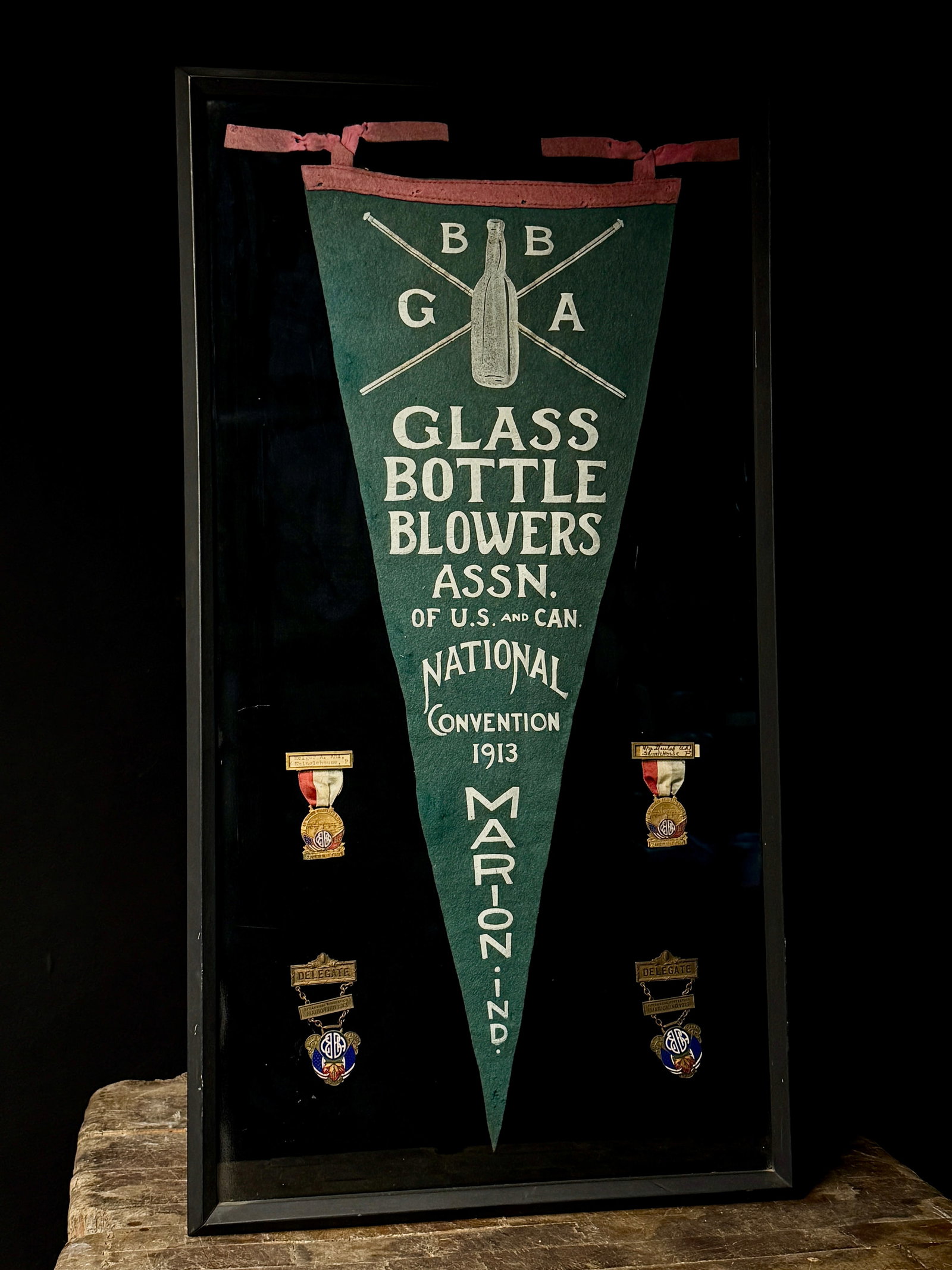 A Collection of Glass Bottle Blowers Association Convention Memorabilia 1913-1918: This professionally framed commemorative display contains ephemera and medals related to the Glass Bottle Blowers Association (GBBA) of the United States and Canada. The central feature is a green fel