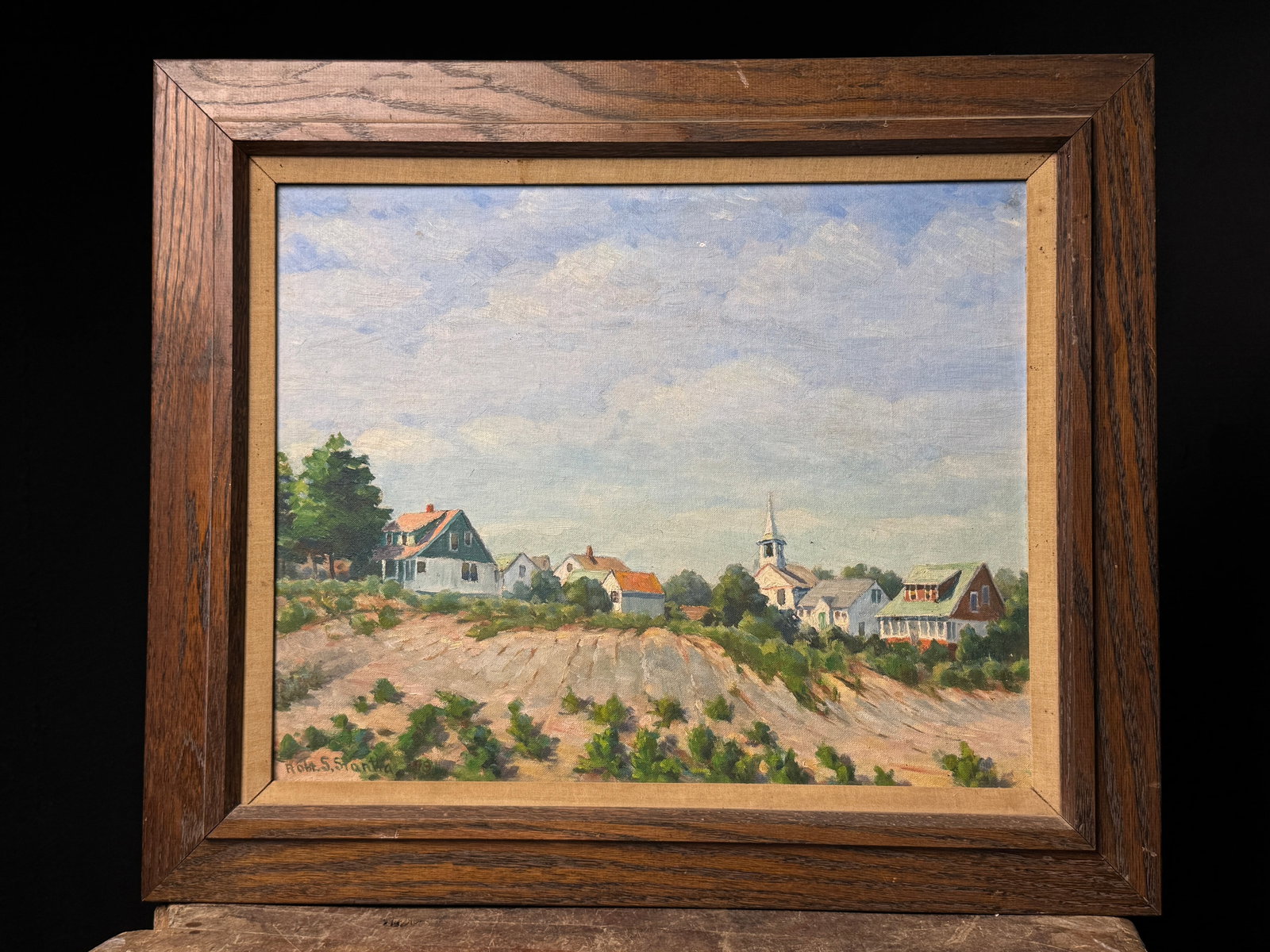 Framed Village Landscape Oil Painting Signed Robt S Stanton: A framed oil landscape painting depicting a village with a church steeple, signed Robt. S. Stanton and dated 1979, measuring approximately 25 by 21 inches.