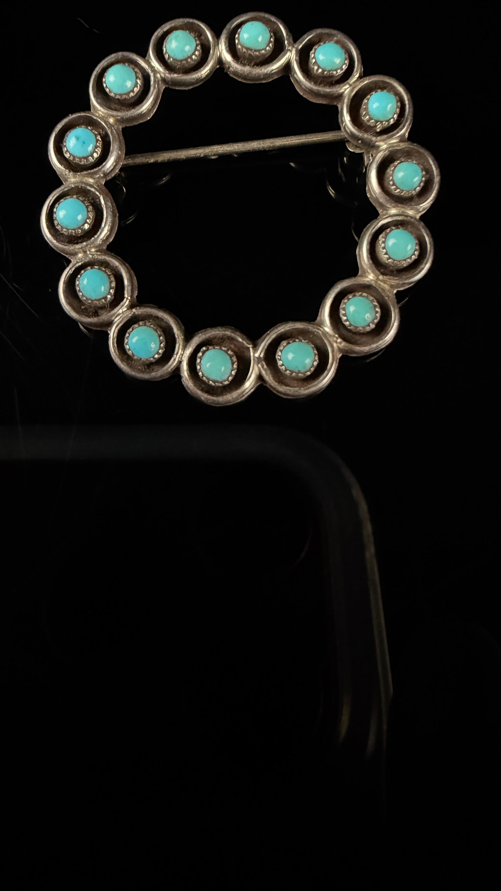 Vintage Native American Turquoise and Sterling Silver Circle Brooch: A vintage circle brooch crafted in the Southwestern Native American style, featuring thirteen round turquoise cabochons. Each stone is individually set in a silver serrated sawtooth bezel. These setti