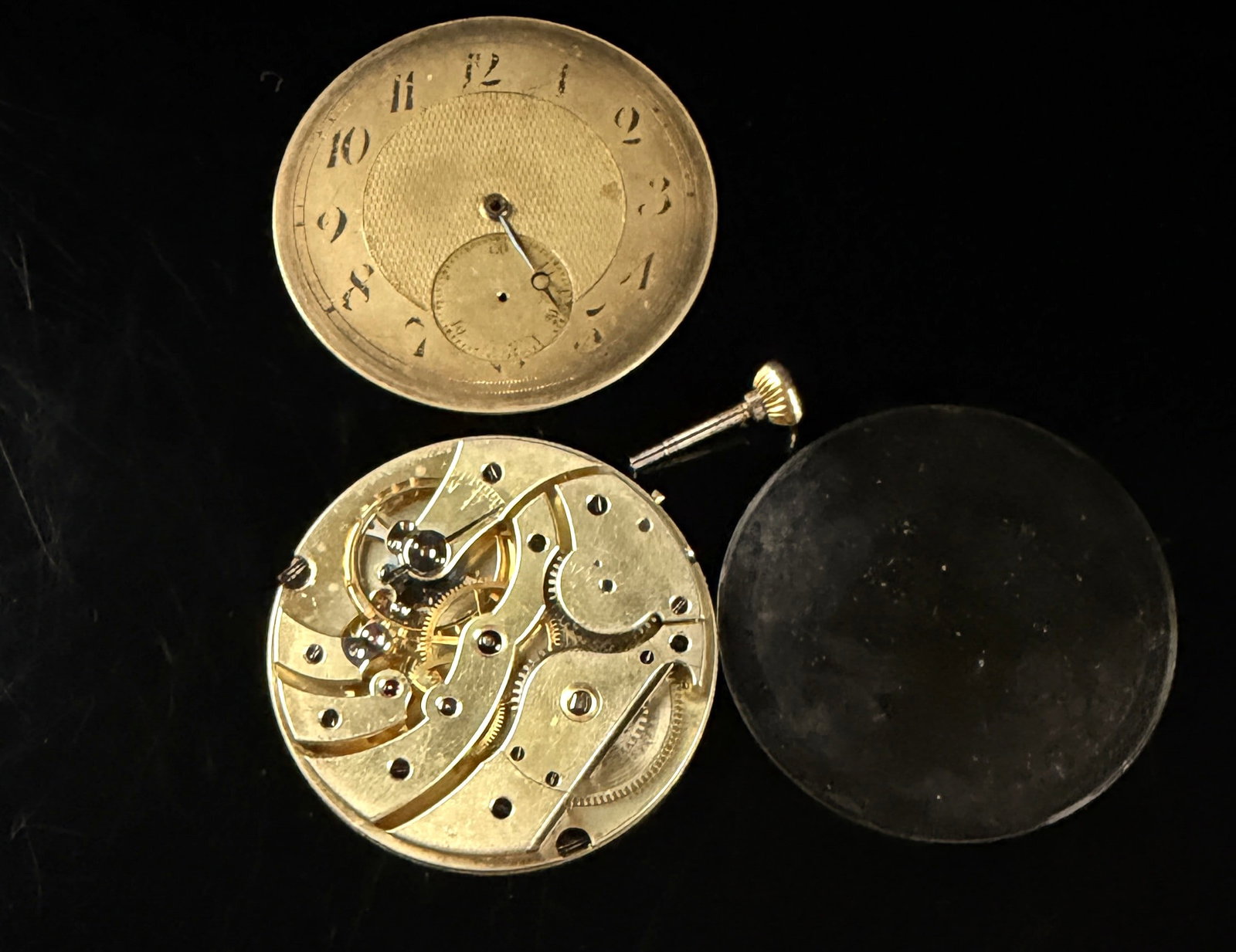 Patek? High-Grade Swiss Pocket Watch Movement and Components: This assortment features the internal components of an antique pocket watch, including a high-grade bridge-plate movement, a textured dial, a crystal, and a winding stem. The manual wind movement is c