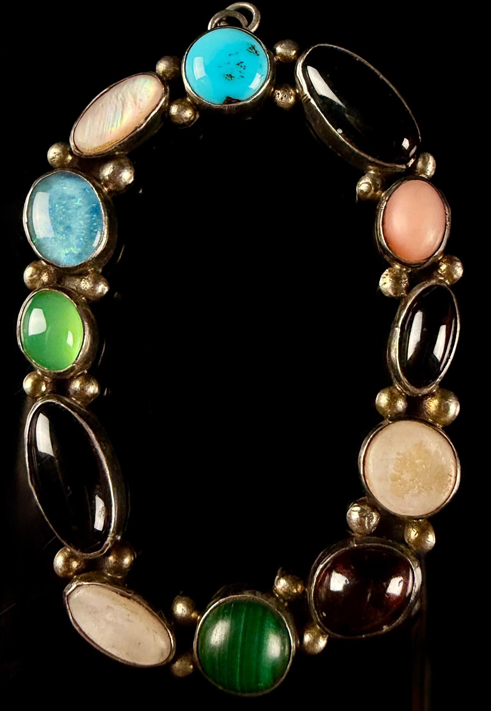 Mexican-Style Silver-Toned and Multi-Stone Oval Pendant: This oval pendant is designed in a style characteristic of Mexican silver jewelry, often associated with mid-century Taxco production. It features twelve bezel-set cabochon gemstones of various colors