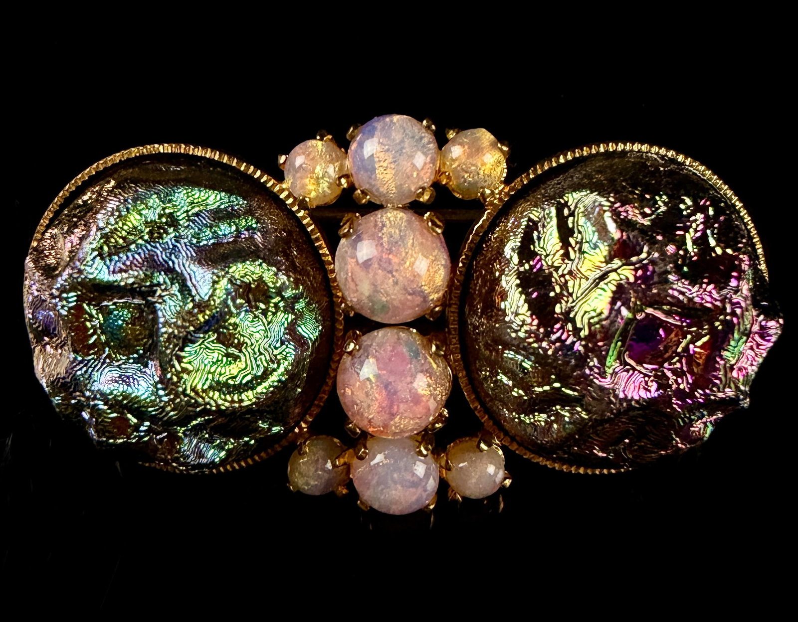 Vintage Germany U.S. Zone Iridescent Lava Glass and Faux Dragon Breath Opal Brooch: This vintage bar-style brooch is constructed from gold-tone base metal and features a combination of art glass and faux opal stones. The design is centered around two large circular art glass cabochon