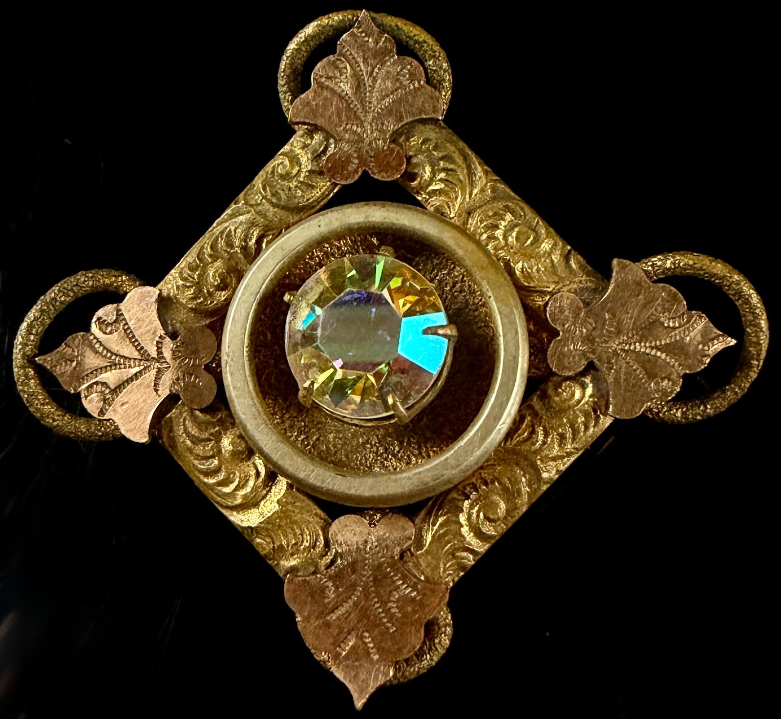 Victorian 1/20 12K Gold Filled Rhombus Brooch with Aurora Borealis Rhinestone: Victorian brooch is designed in a rhombus shape and constructed from 12 karat gold-filled metal. The yellow-tone body features engraved scrollwork ornamentation throughout. Applied to each of the four