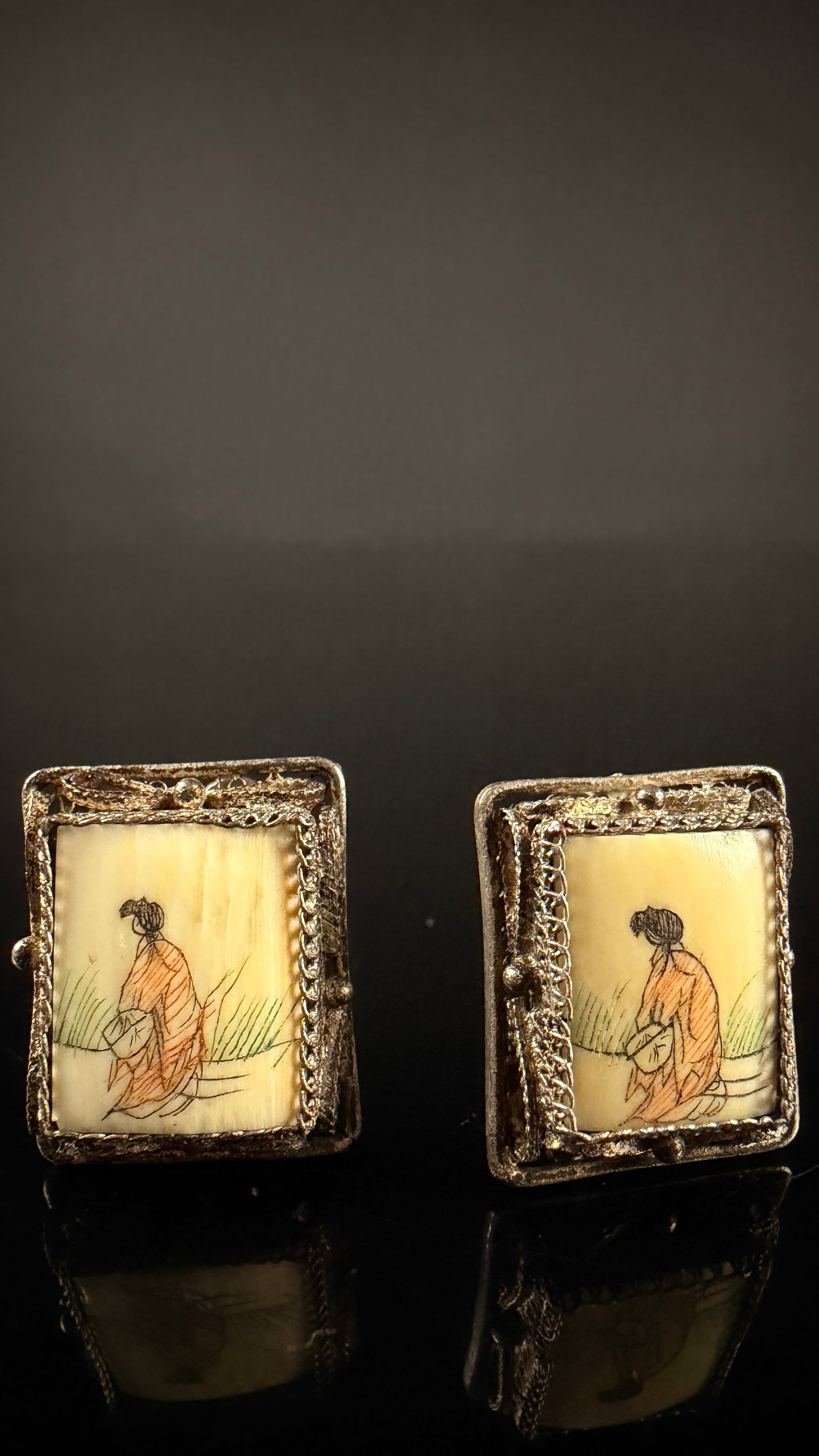 A Pair of Vintage Japanese Style Hand-Painted Bone and Silver Filigree Earrings: A pair of vintage screw-back earrings featuring rectangular panels of hand-painted natural organic material, likely bone. Each panel depicts a miniature scene of a female figure in a kimono, possibly 