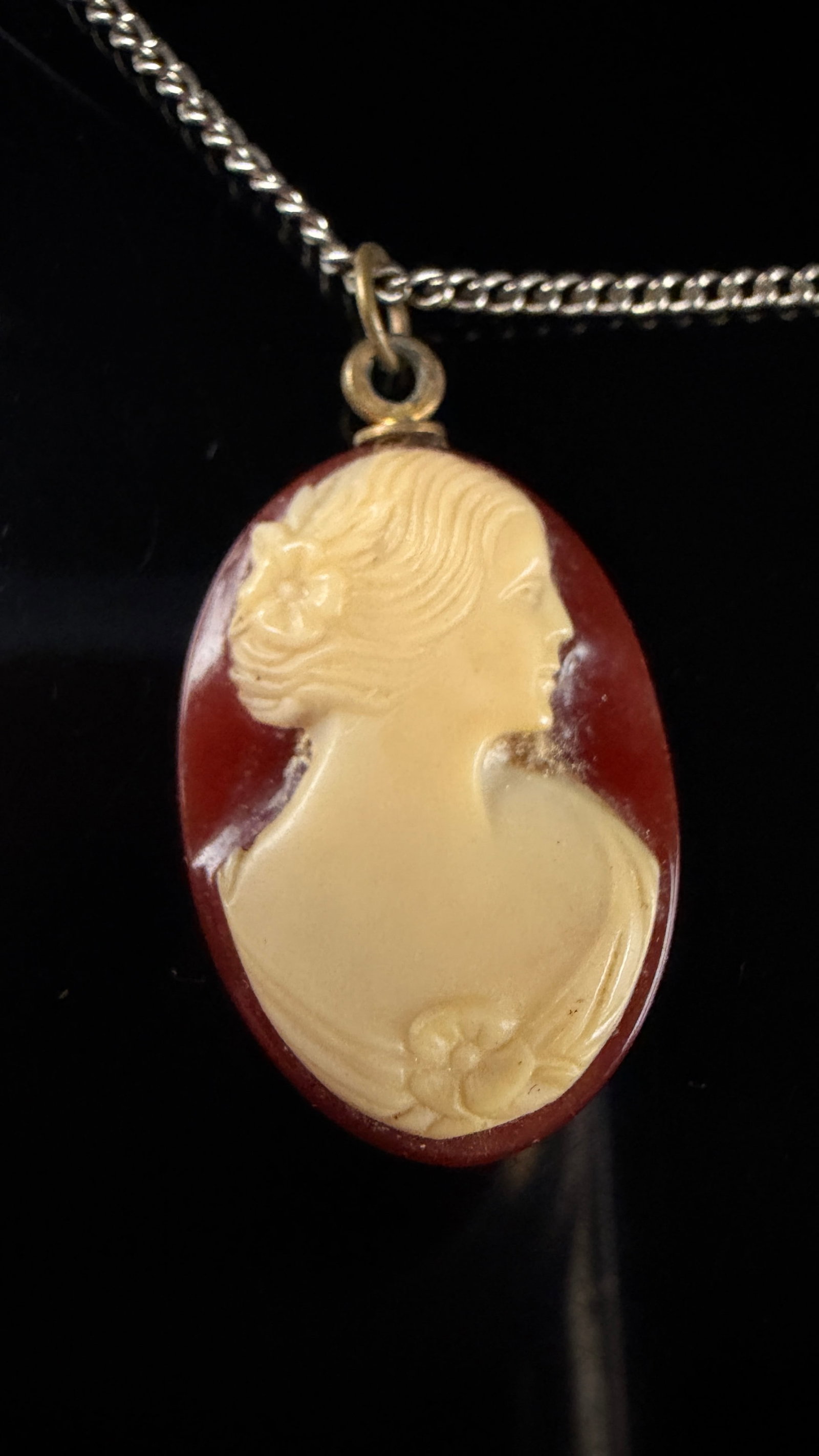 A Vintage Cameo Pendant Necklace and Matching Screw-Back Earrings: This vintage jewelry suite consists of a cameo pendant necklace and a pair of matching stud-style earrings. The oval pendant features a relief-carved cameo of a female profile facing right, rendered i