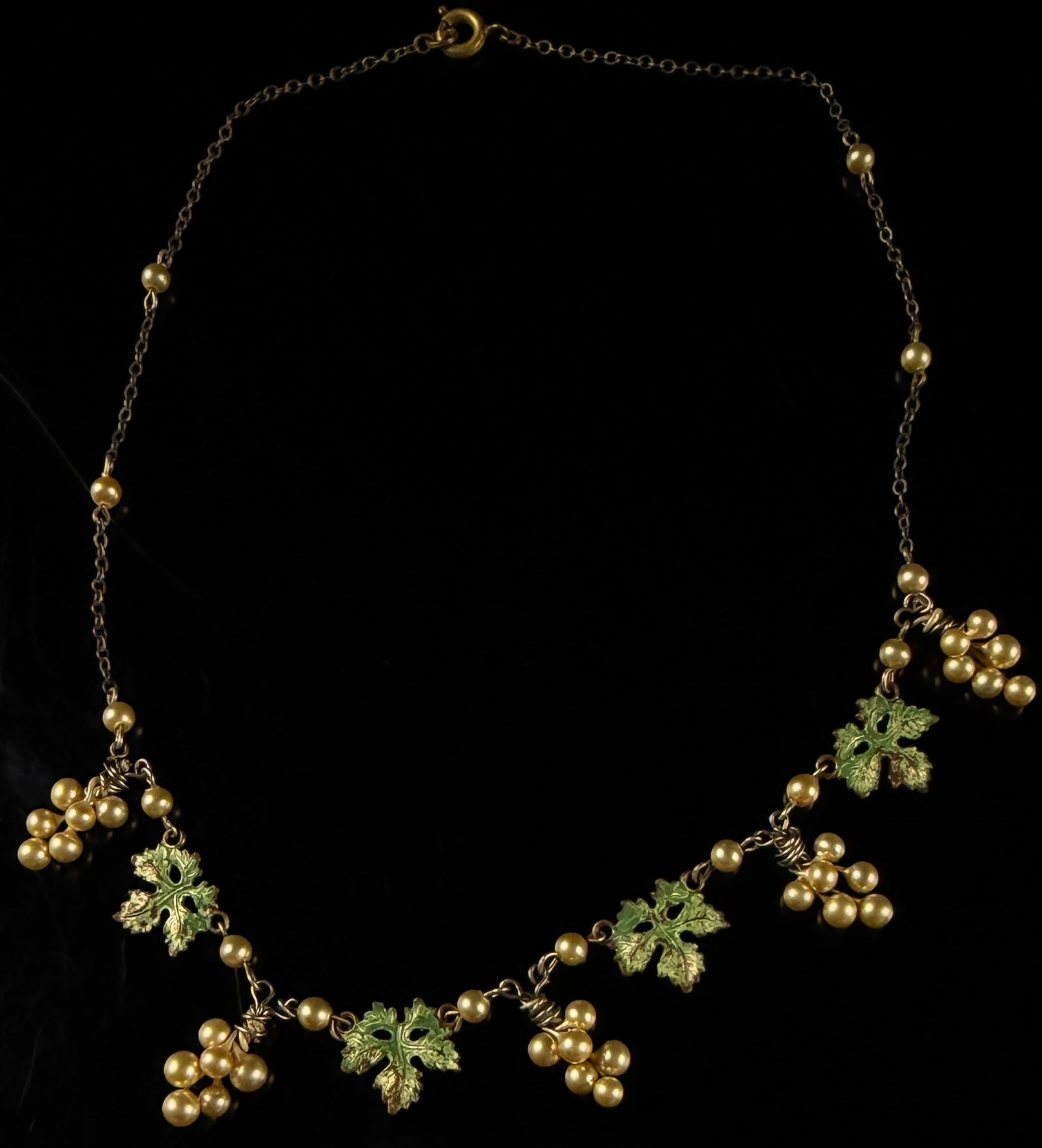 Mid-Century 12K Gold-Filled Faux Pearl and Green Enamel Grape Motif Festoon Necklace: A vintage mid-century festoon-style necklace featuring a grape and leaf motif. The piece is constructed from a fine link chain interspersed with small pearlescent bead stations. The central decorative