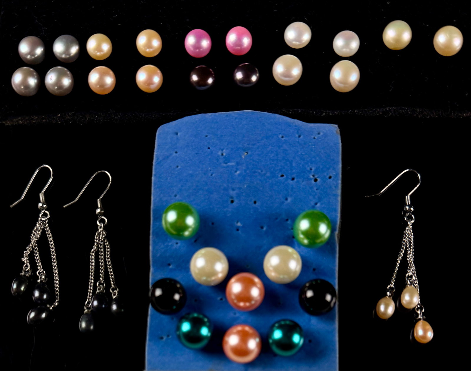 An Assortment of Multi-Color Cultured and Simulated Pearl-Style Earrings in Silver-Tone Metal: An assortment of pearl-style earrings featuring various colors, shapes, and designs. The collection includes several round stud earrings and triple-strand drop earrings. Colors present include white, 
