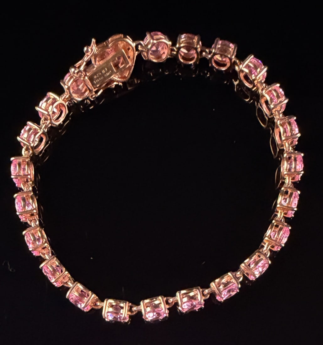 RJ Sterling Silver Rose Gold-Tone Pink and Clear Stone Heart Clasp Tennis Bracelet: This tennis-style link bracelet is crafted from sterling silver with a rose gold-tone finish. The design features a continuous row of prong-set, round-cut pink stones. The integrated box clasp is embe