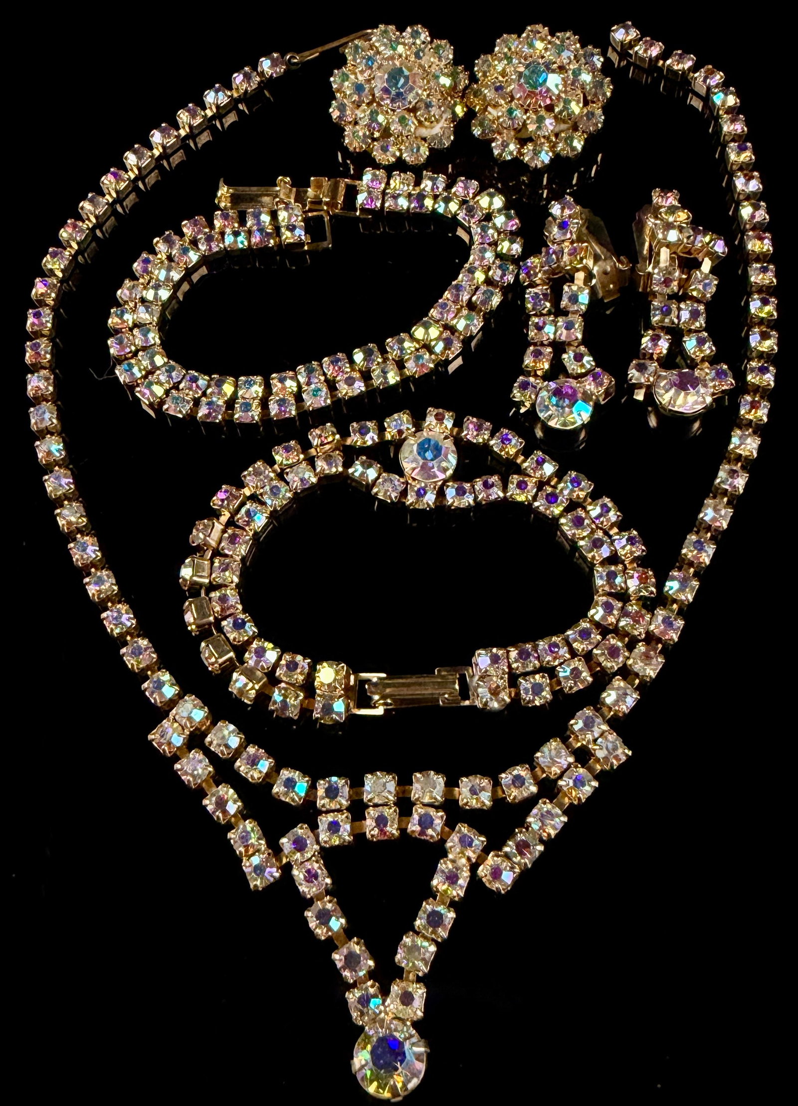 Five-Piece Suite of Mid-Century Aurora Borealis Rhinestone Costume Jewelry: A five-piece collection of vintage costume jewelry from the mid-20th century, featuring iridescent Aurora Borealis glass rhinestones set in gold-tone base metal. The suite includes one necklace, two b