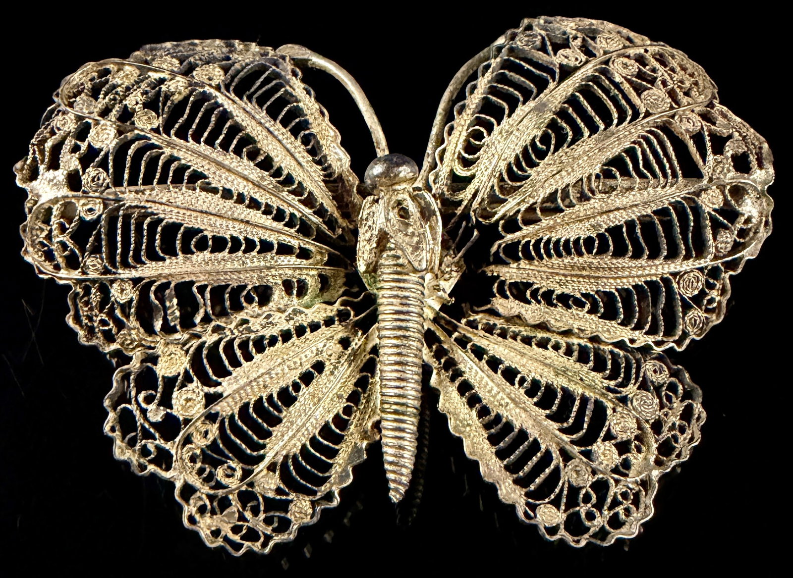Vintage Silver-Tone Filigree Butterfly Brooch: This vintage butterfly brooch features intricate filigree construction. The wings are designed with fine-gauge, hand-manipulated silver-tone wires forming scrolled and looped patterns within a structu