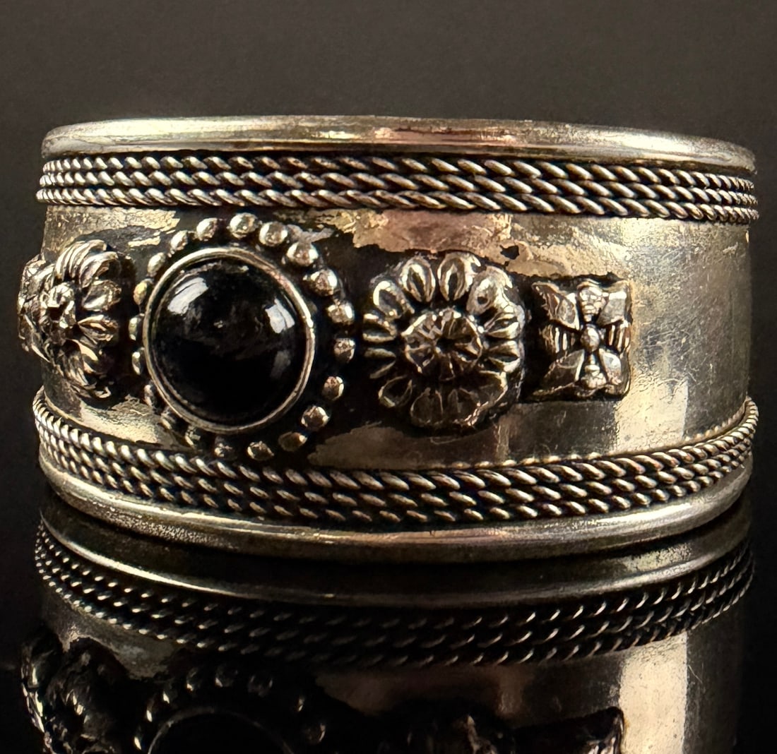 Tibetan Style Silver Toned White Metal Cuff Bracelet with Black Cabochon Stone: This is an ethnic-style wide open-cuff bracelet crafted from a silver-toned white metal. The design features a central decorative band with a bezel-set round black cabochon stone, likely black onyx or