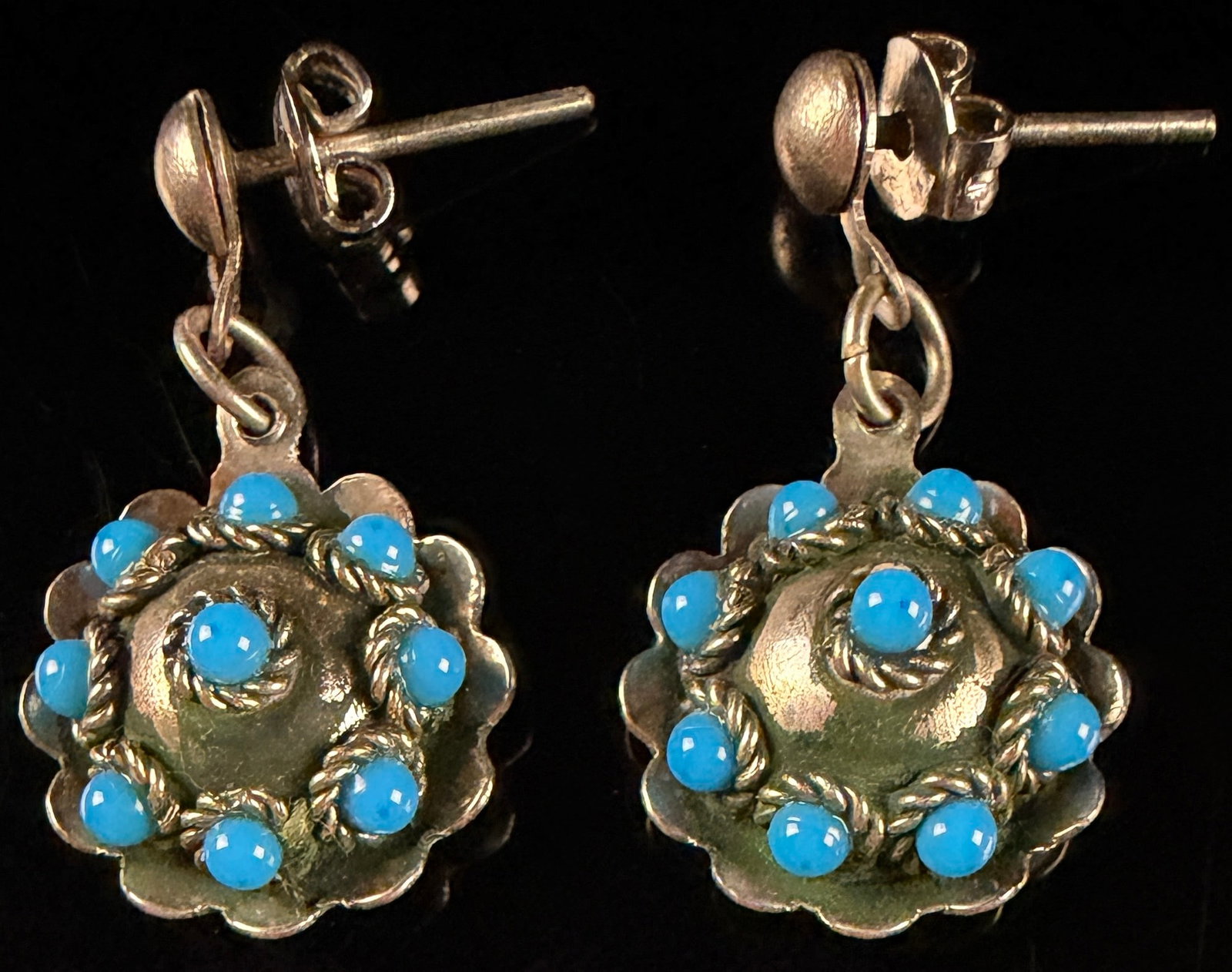 A Pair of Vintage Silver Toned and Turquoise Cabochon Cluster Dangle Earrings: This is a matched pair of vintage dangle earrings, each featuring a circular domed drop with a scalloped perimeter. The drops are set with nine bright blue round cabochons, arranged as a single centra