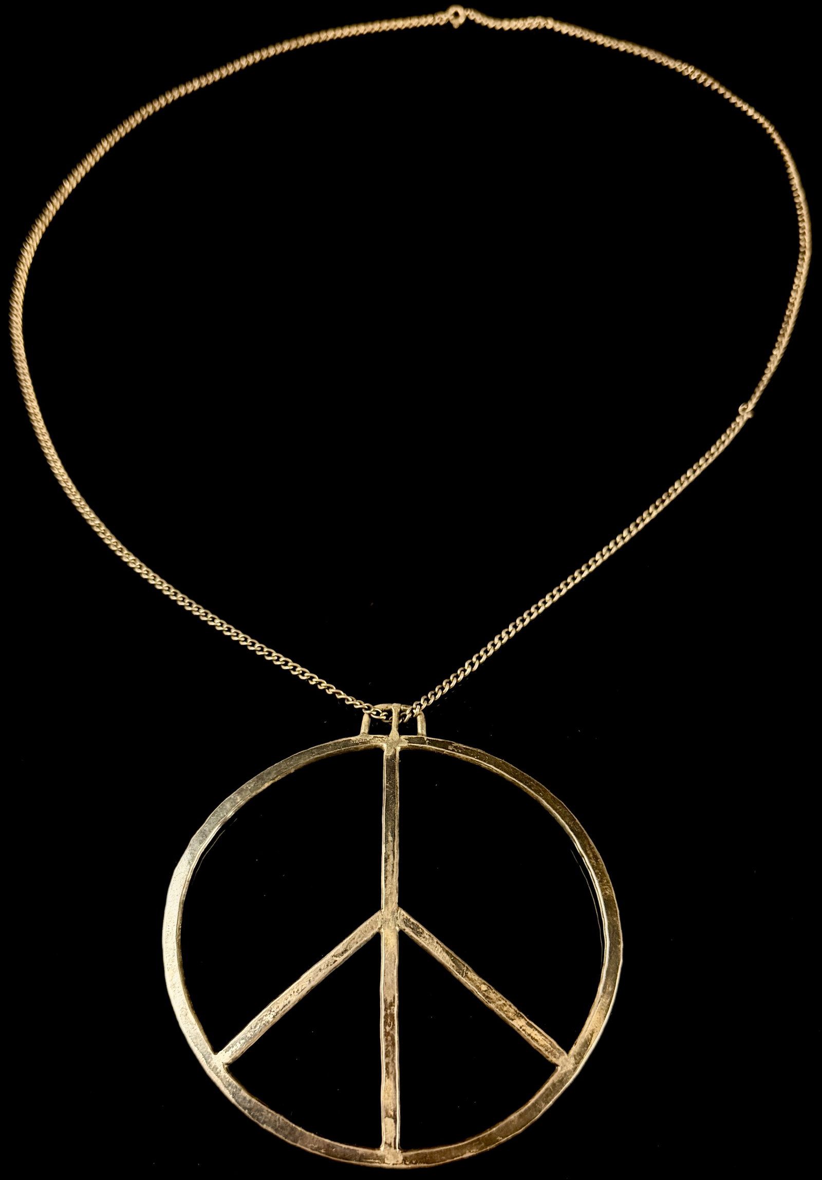 Large Sterling Silver Hammered Peace Sign Pendant Necklace: A large sterling silver pendant necklace featuring a classic openwork circular peace sign symbol. The pendant displays a hand-hammered, textured surface finish. It is suspended from a fine curb link c
