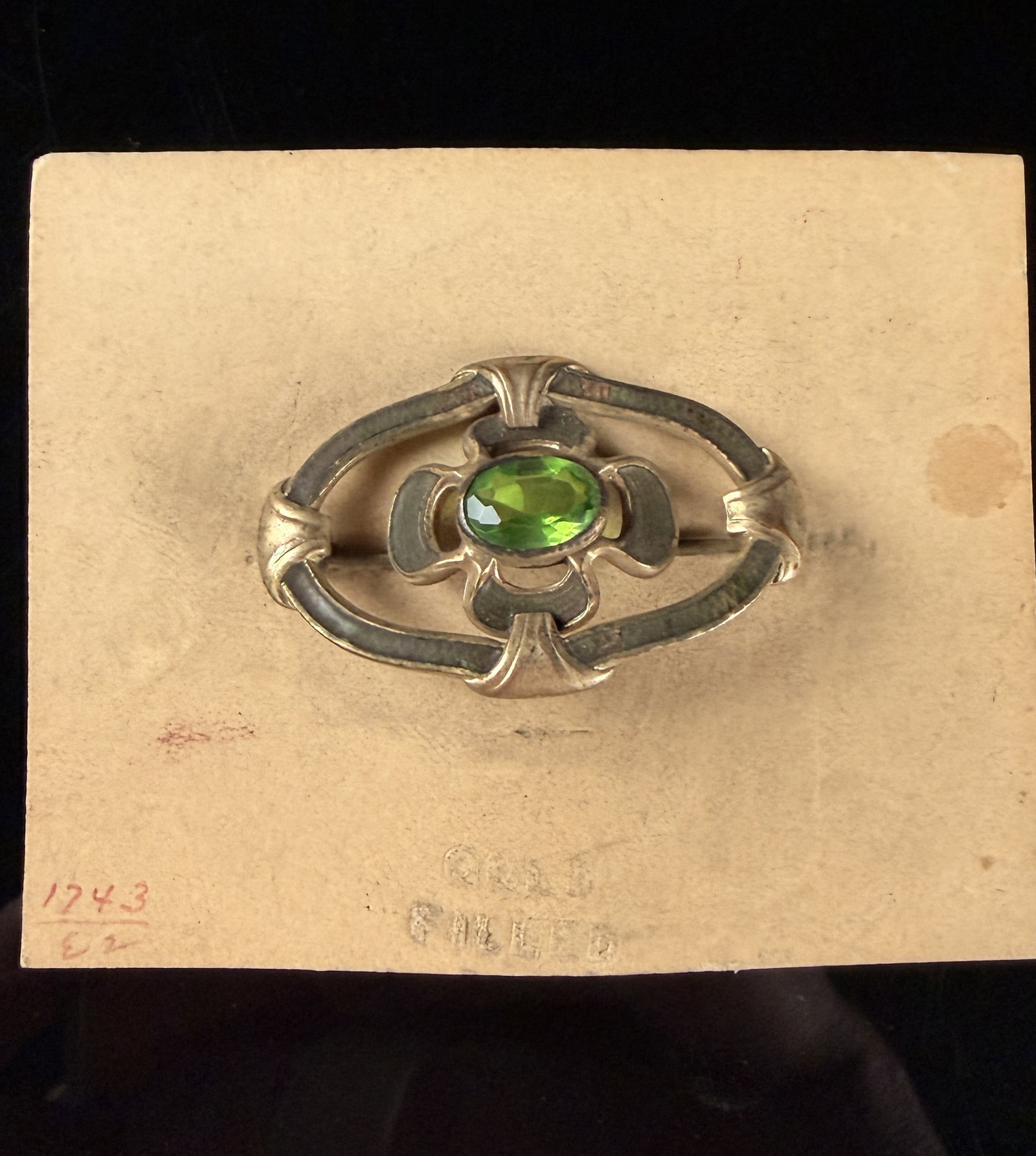 Antique Arts and Crafts Style Gold Filled and Green Stone Brooch: This antique early 20th-century gold-filled brooch is designed in the Arts and Crafts style. The piece features an oval openwork frame with foliate accents located at the four cardinal points. At the 