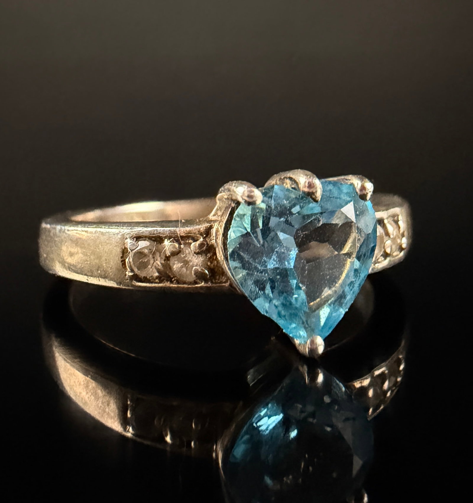 The Genuine Gemstone Company Annabella Collection Swiss Blue Topaz and Sterling Silver Heart Ring: This sterling silver ring is part of the Annabella collection by The Genuine Gemstone Company (TGGC). It features a central heart-cut Swiss blue topaz secured by a three-prong basket setting. The