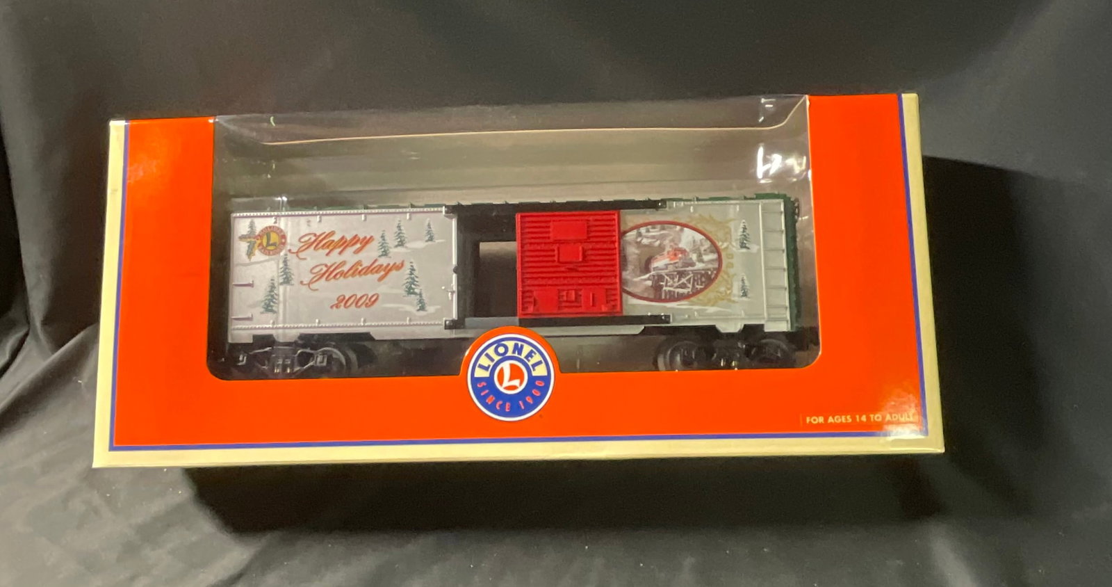 Lionel 6-25066 O Gauge 2009 Happy Holidays Christmas Boxcar: This Lionel O Gauge model railroad boxcar, model number 6-25066, was released as part of the 2009 holiday collection. The boxcar features a silver-colored plastic body with a functional red sliding si