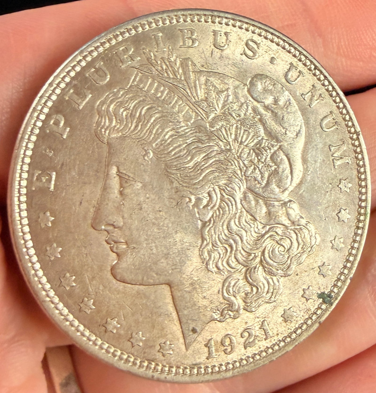 1921 US Morgan Silver Dollar, Philadelphia Mint: This US 1921 Morgan silver dollar was struck at the Philadelphia Mint. The coin is composed of 90% silver and 10% copper. It features the standard Morgan design on the obverse and the eagle reverse de