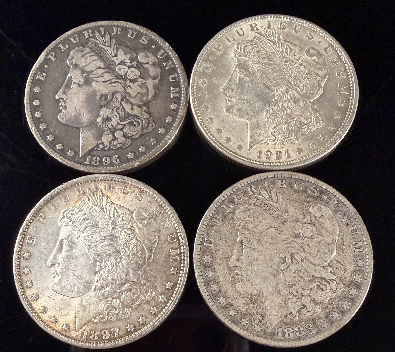 A Collection of US Morgan Silver Dollars: A collection of US Morgan silver dollars struck between 1883 and 1921. These coins are composed of 90% silver and 10% copper. The obverse features the Morgan Liberty Head design facing left, wearing a