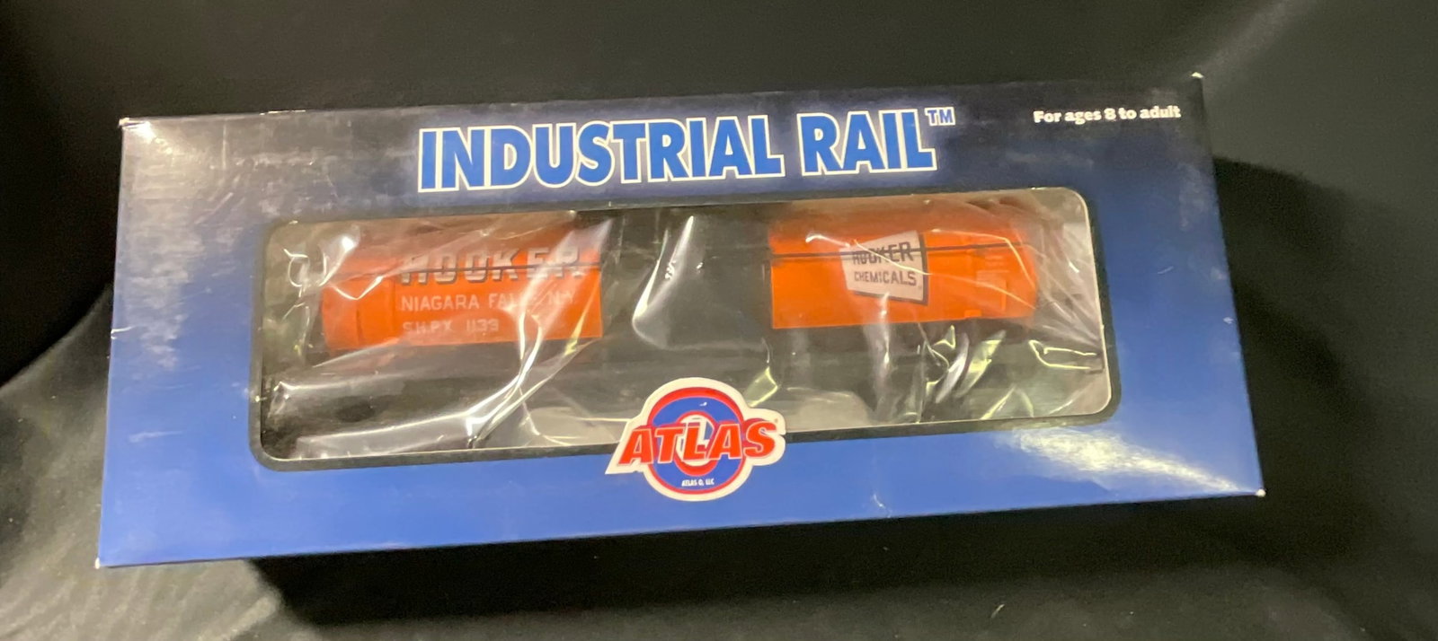 Atlas O Industrial Rail Hooker Chemicals Tank Car: This lot features an O-Scale model railroad tank car produced by Atlas O, LLC as part of the Industrial Rail product line. The car is constructed of plastic and metal components, featuring a bright or