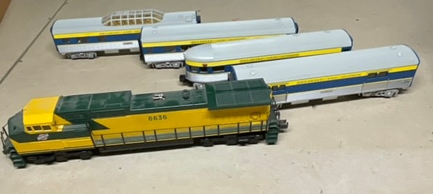 M.T.H. Electric Trains O-Gauge Diesel Locomotive and Passenger Car Set: This O-gauge model train group is manufactured by M.T.H. Electric Trains, as evidenced by molded marks on the underside of each piece. The set consists of a modern diesel locomotive and a collection o