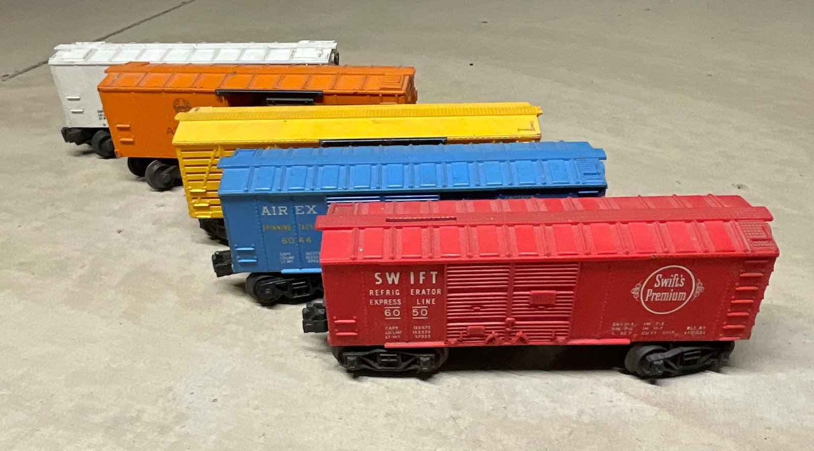 A Collection of Five Vintage Lionel O-Gauge Freight Cars: This lot consists of five vintage O-gauge model train freight cars manufactured by Lionel. The collection features plastic bodies with a mix of plastic and die-cast metal trucks and includes the follo