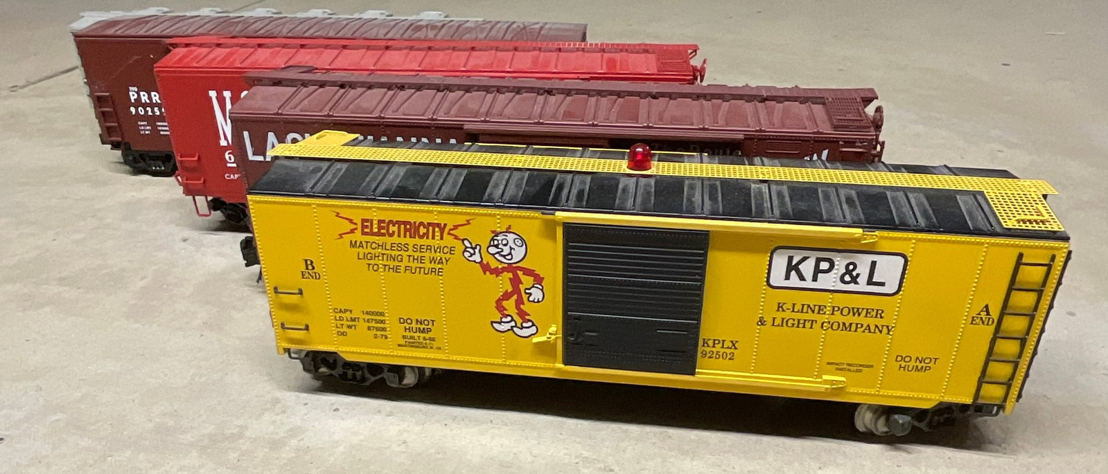 Five Lionel and K-Line O-Gauge Model Train Freight Cars including Operating Voltmeter Boxcar: Five O-gauge model train freight cars manufactured by Lionel and K-Line. The collection is constructed primarily of molded plastic with metal wheels and axles and features operating knuckle-style coup