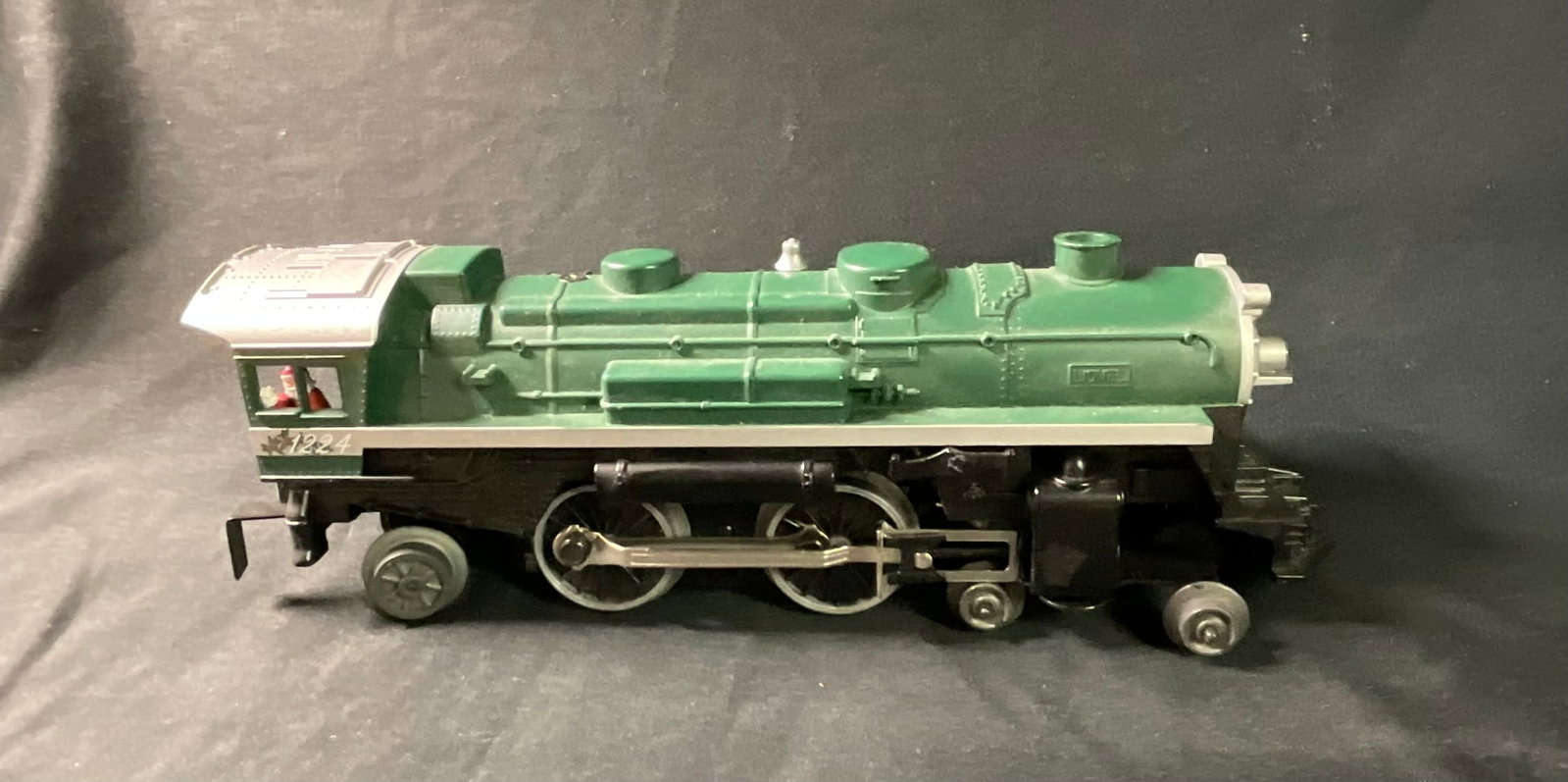 Lionel 1224 O-Gauge 2-4-2 Christmas Steam Locomotive: This is a Lionel O-gauge 2-4-2 Columbia-type steam-style electric locomotive, model number 1224. The item features a holiday-themed design with a green molded plastic boiler shell, a silver-toned cab 