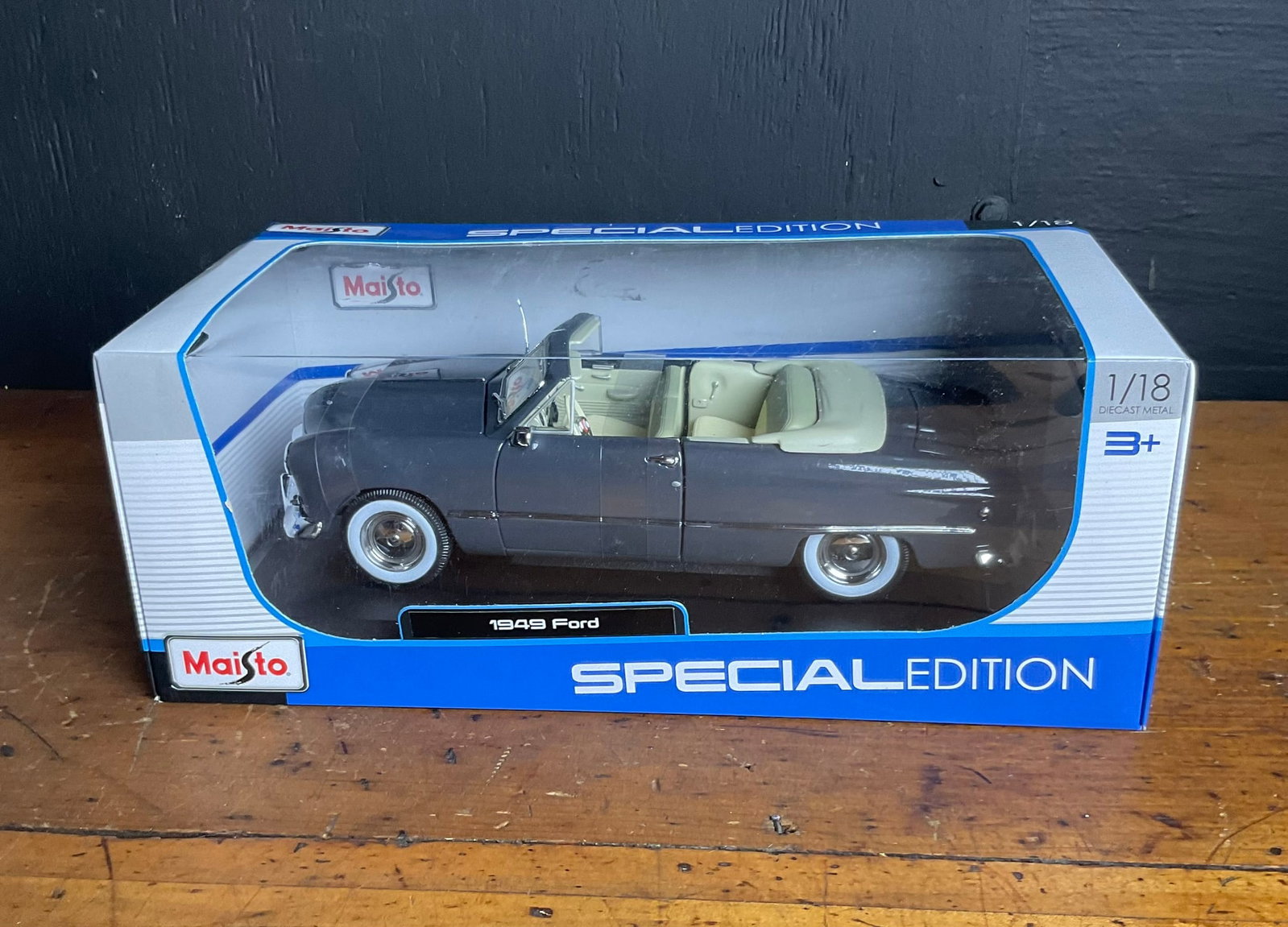 Maisto Special Edition 1/18 Scale 1949 Ford Convertible Die-cast Model Car: This Maisto Special Edition model depicts a 1949 Ford convertible in 1/18 scale. The vehicle is constructed from die-cast metal with plastic components. It is finished in a dark gray exterior with a c