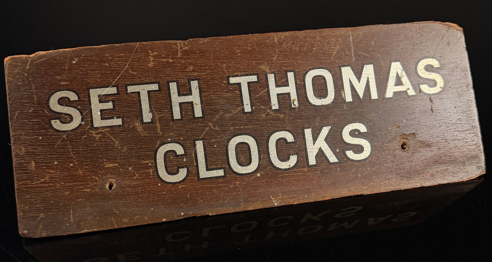 Vintage Seth Thomas Clocks Wooden Advertising Counter Sign: This vintage wooden advertising sign features branding for the Seth Thomas Clock Company. Constructed from a solid rectangular wood block with a dark brown stain, the piece likely served as a counter-
