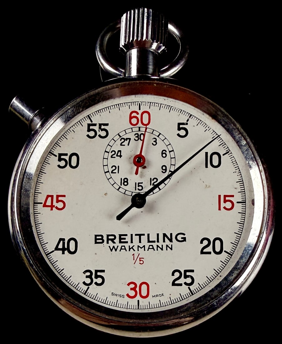 Breitling Wakmann 1/5 Second Mechanical Stopwatch: This vintage Swiss-made mechanical stopwatch features a white dial with dual Breitling and Wakmann branding. The dial is configured with a 60-second outer track featuring 1/5-second increments and a 3