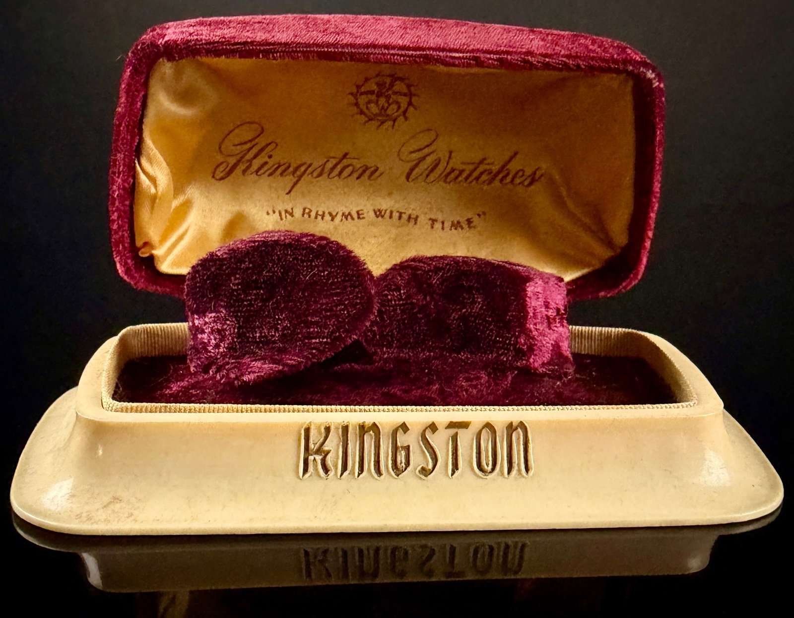 Vintage Kingston Watches Art Deco Style Presentation Box: A mid-20th-century watch display box manufactured for Kingston Watches. The presentation box features a flared cream-toned plastic base and a domed lid covered in deep burgundy velvet. The interior li