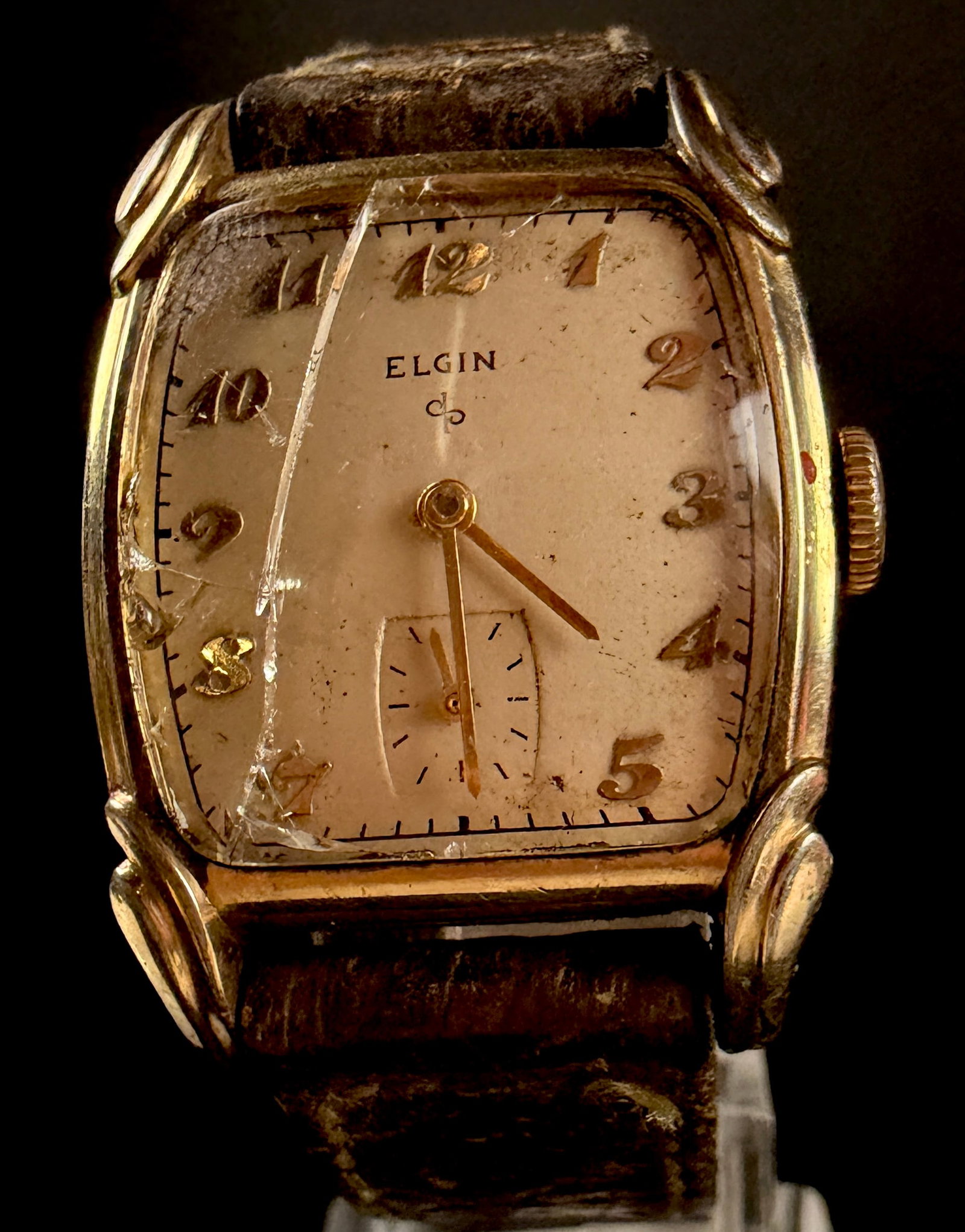 Vintage Elgin 10K RGP Men's Manual Wind Wristwatch Grade 554 Reference 6717: This vintage men's wristwatch by the Elgin National Watch Company features a tonneau-shaped case with distinctive stylized lugs. The case construction includes a 10 karat rolled gold plate bezel and a