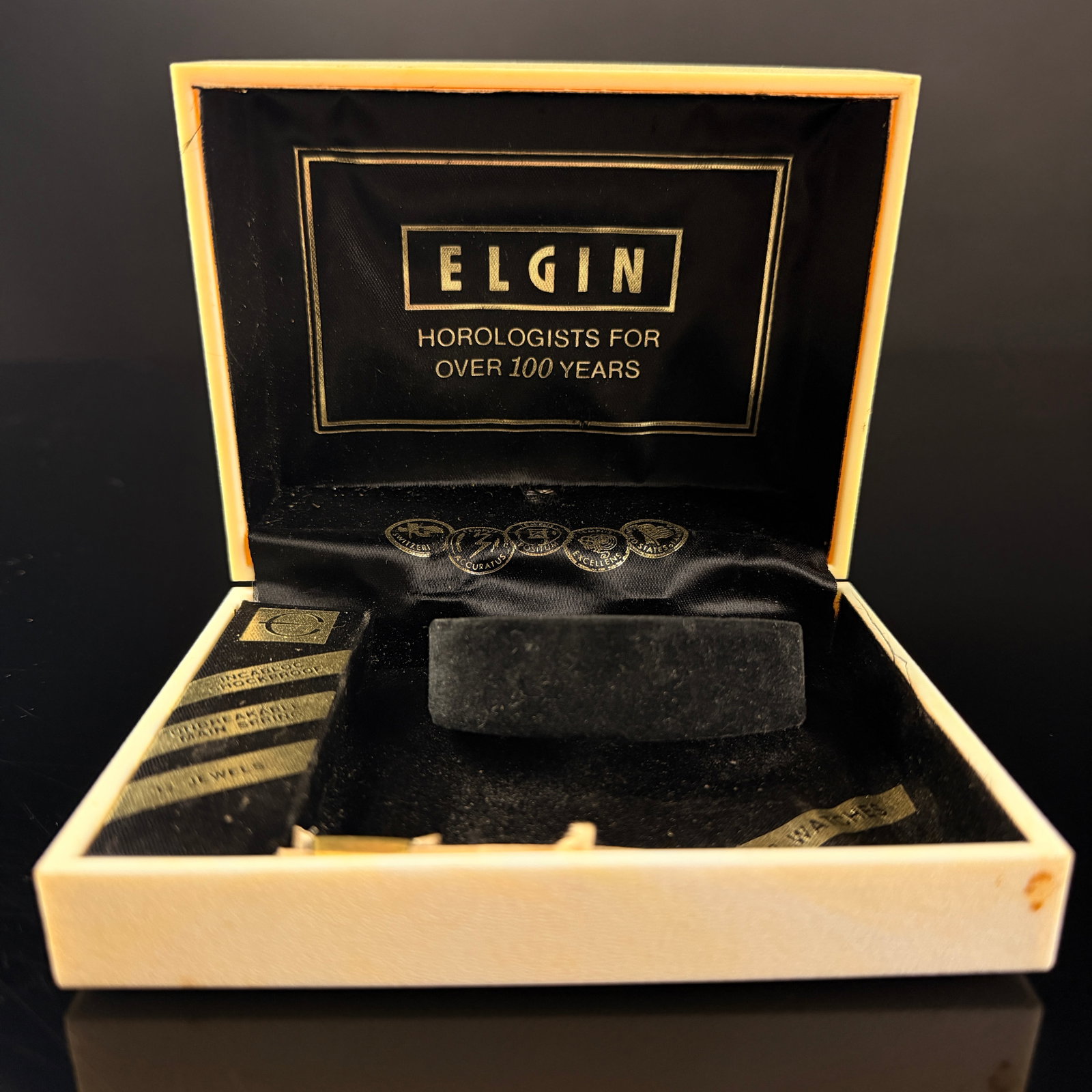 Vintage Elgin Marbled Plastic Watch Presentation Box: A vintage empty watch presentation box by Elgin. The exterior is constructed from molded cream-colored marbleized plastic with a hinged lid. The lid features a silver-tone stylized E logo and the bran