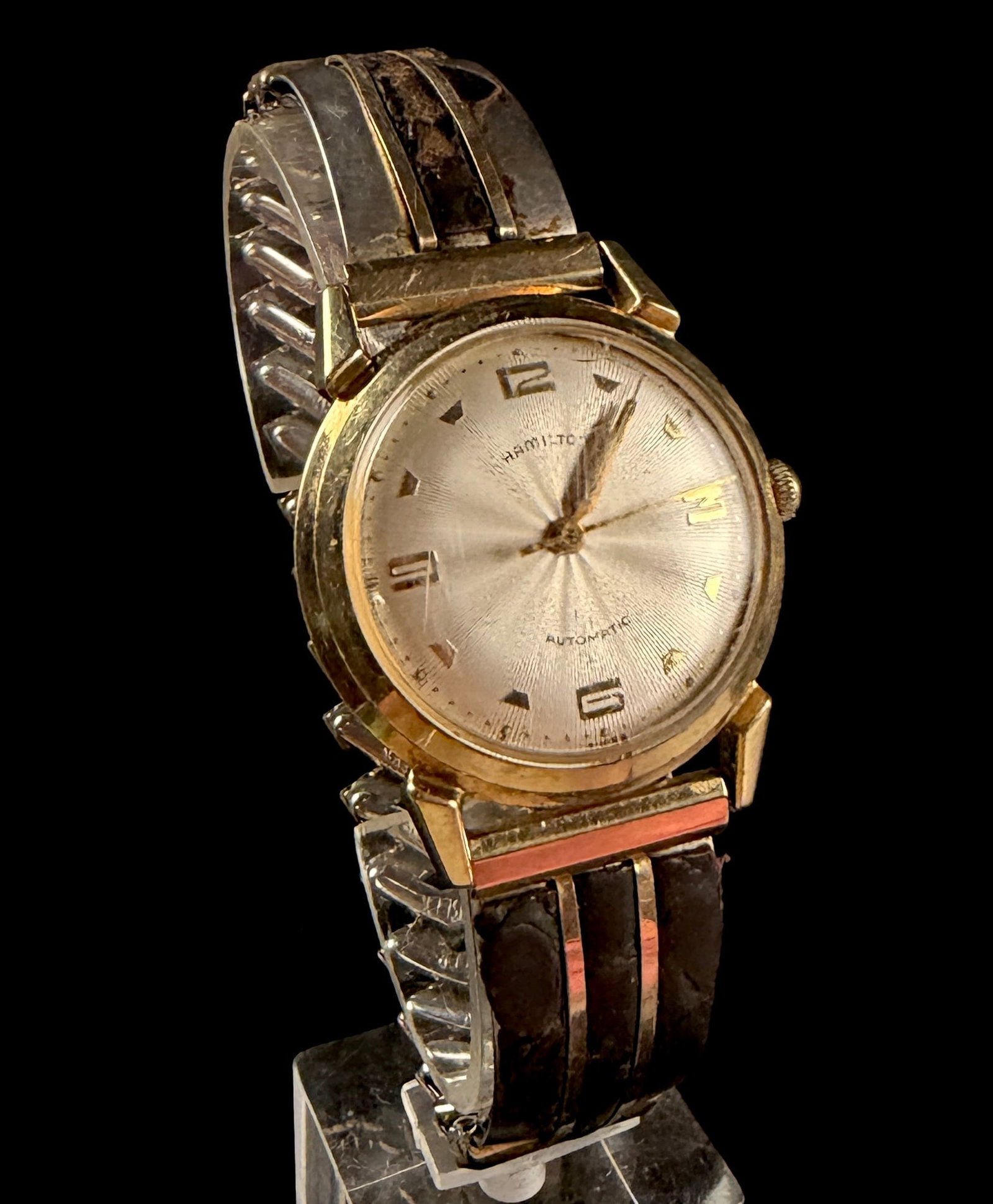 Hamilton Accumatic III Automatic Wristwatch: A vintage Hamilton Accumatic III automatic wristwatch featuring a 10K rolled gold plate bezel and a stainless steel screw-down case back. The silver-tone dial displays a sunburst texture with applied 