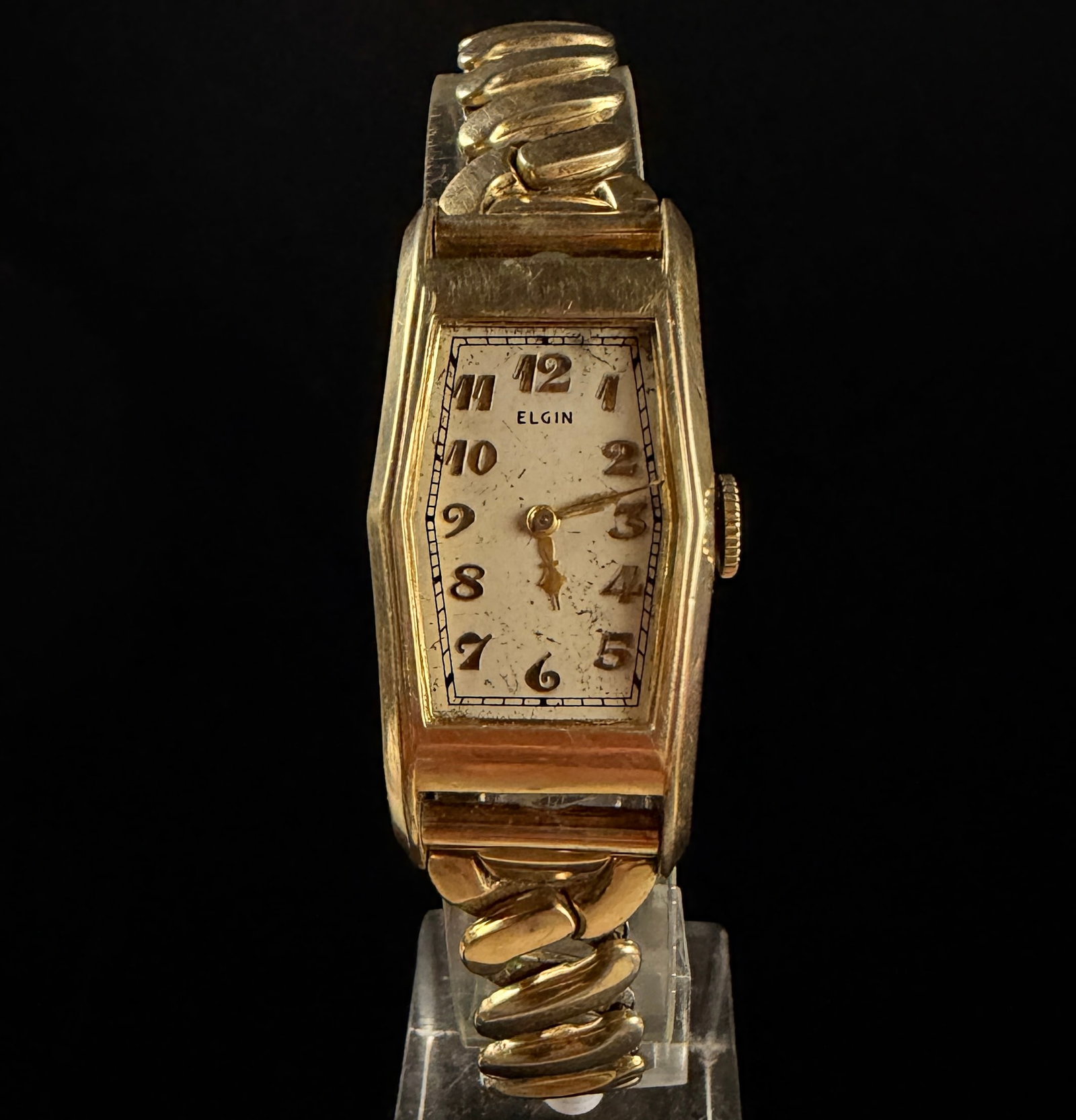 Vintage 1937 Elgin Art Deco Gold Tone Tonneau Wristwatch with Gemex Expansion Bracelet: A vintage manual wind wristwatch produced by the Elgin National Watch Co. circa 1937. The watch features an Art Deco tonneau-shaped case constructed of gold-tone plated base metal, manufactured by the